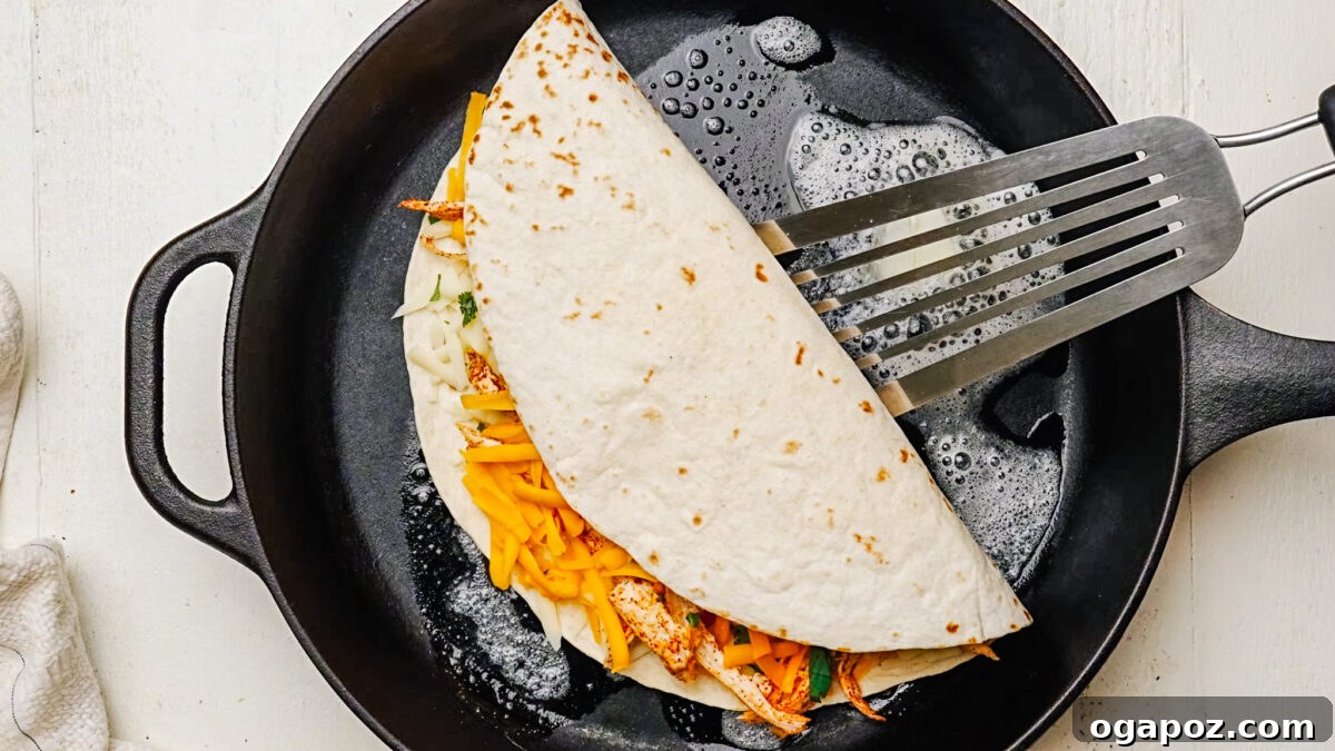 Ultimate Chicken Quesadilla 7 Chicken quesadilla cooking in a skillet with butter, turning golden brown on the outside.