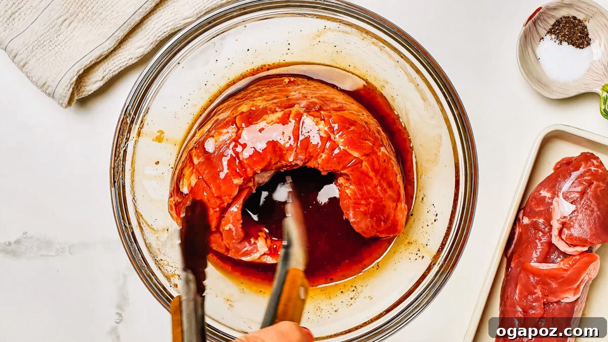 Irresistibly Juicy Pork Tenderloin Marinade 5 Pork tenderloin marinating in a shallow bowl with the marinade.