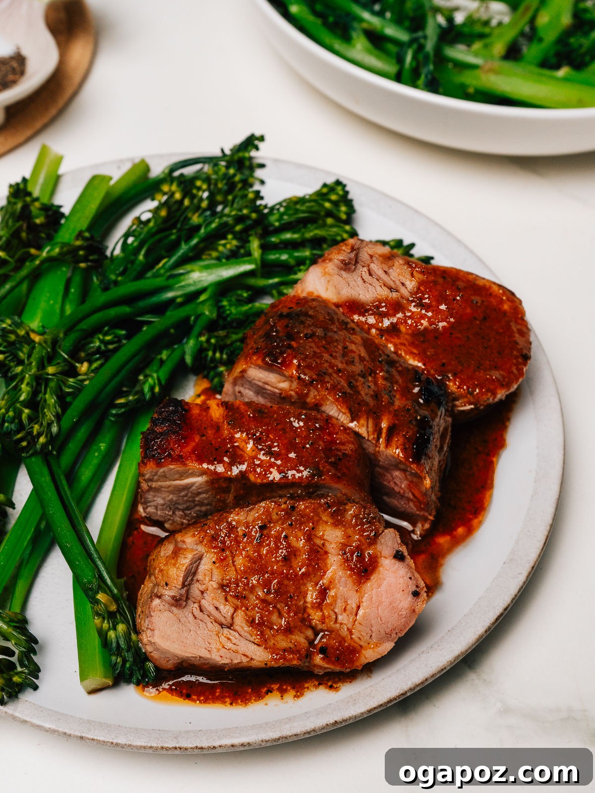 Irresistibly Juicy Pork Tenderloin Marinade 7 Beautifully plated pork tenderloin slices with reduced marinade glaze, served alongside vibrant broccolini.