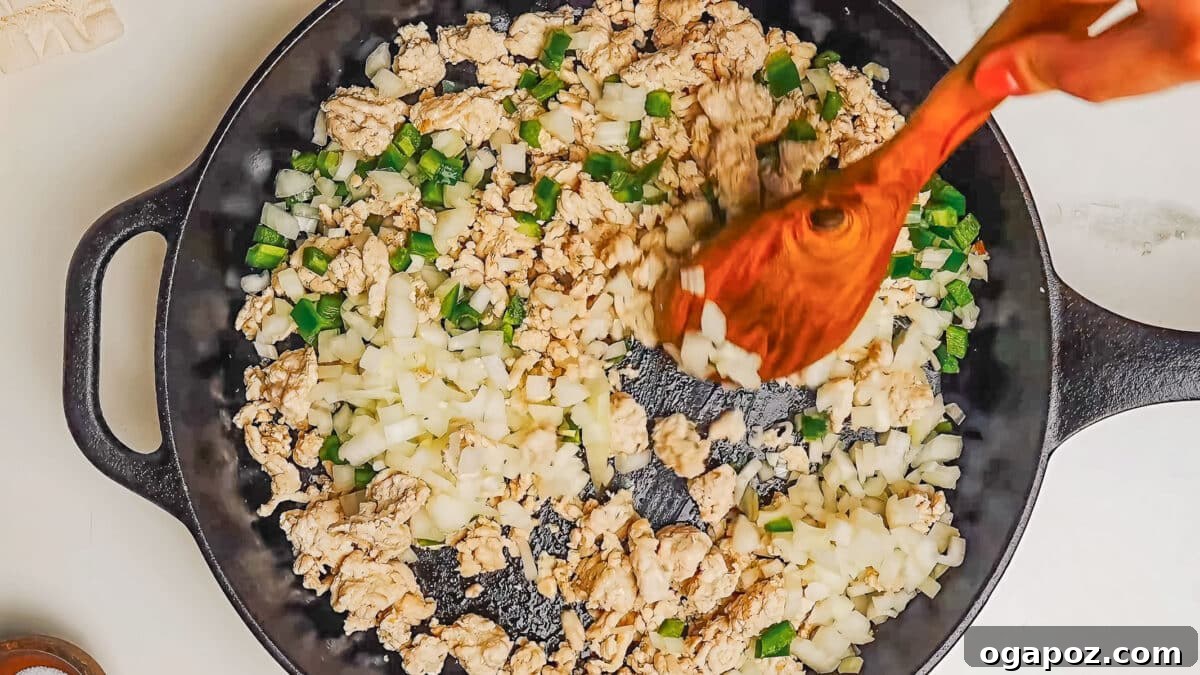 Step 2: Adding chopped onions, jalapeno, and garlic to the browned turkey in the skillet.