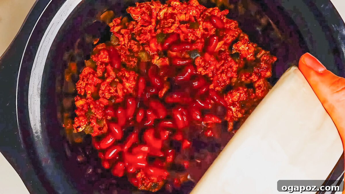 Step 4: Transferring the sautéed turkey mixture to the slow cooker with beans, tomatoes, and water.