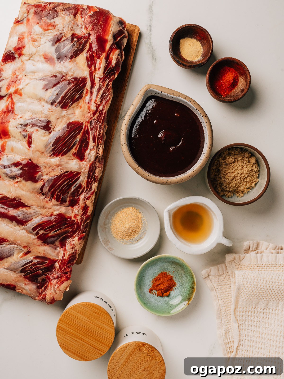 Fall-Off-The-Bone Oven Ribs 3 Beef back ribs recipe ingredients laid out on a cutting board, including spices, brown sugar, and apple cider vinegar.