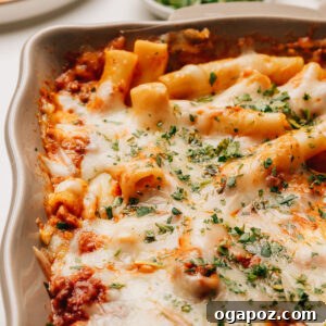 Baked ziti with ricotta topped with minced parsley, featuring a golden, bubbling cheese crust.