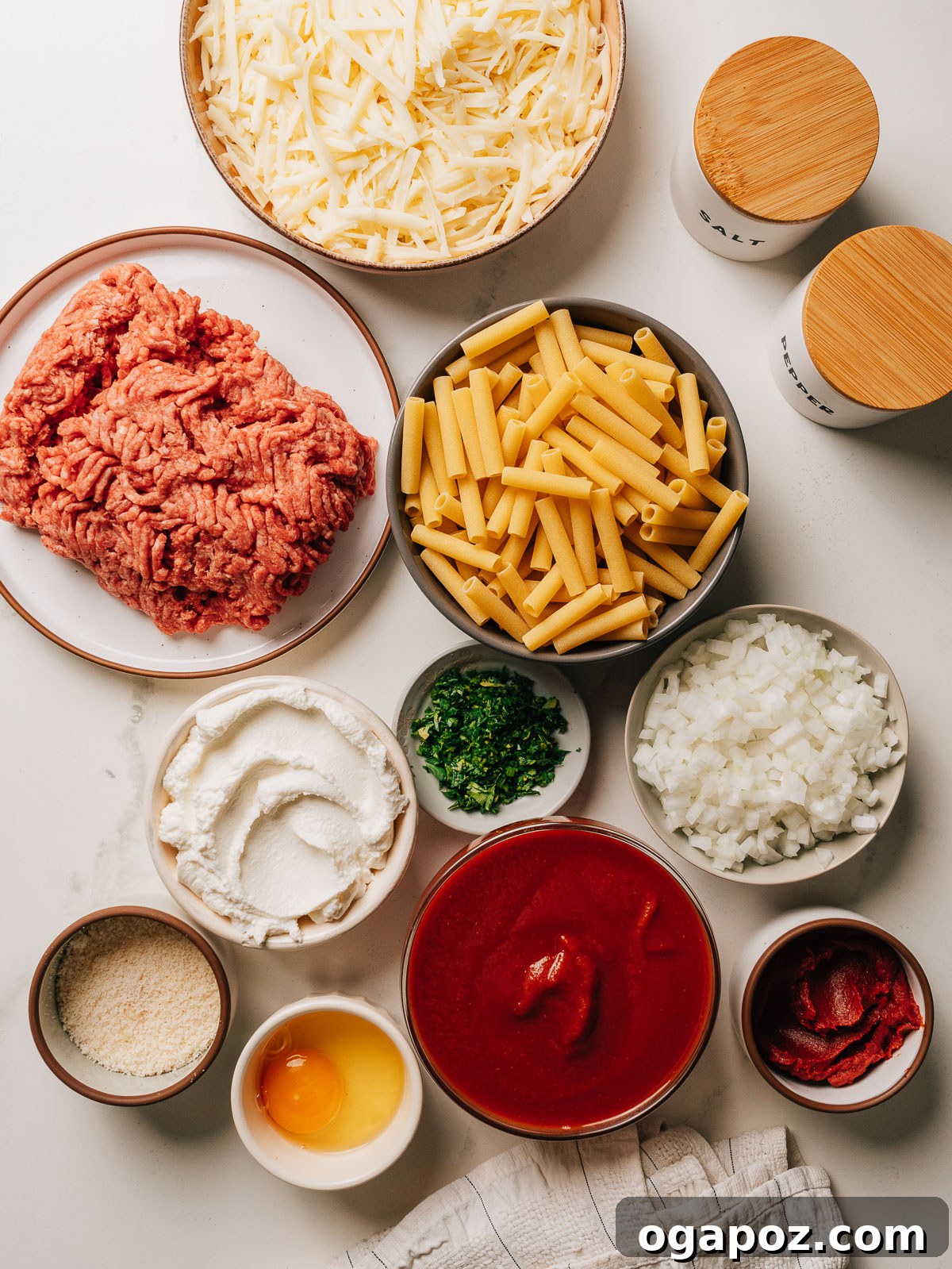 Creamy Ricotta Baked Ziti 3 Ingredients for baked ziti including ziti pasta, ground beef, creamy ricotta, rich mozzarella, crushed tomatoes, and fresh herbs, all ready for assembly.