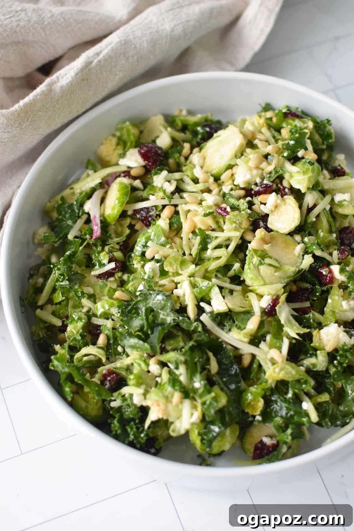 Shaved Brussels and Kale Salad 9 A large, beautifully presented Kale Brussels Sprout Salad, glistening with dressing, in a rustic wooden bowl.