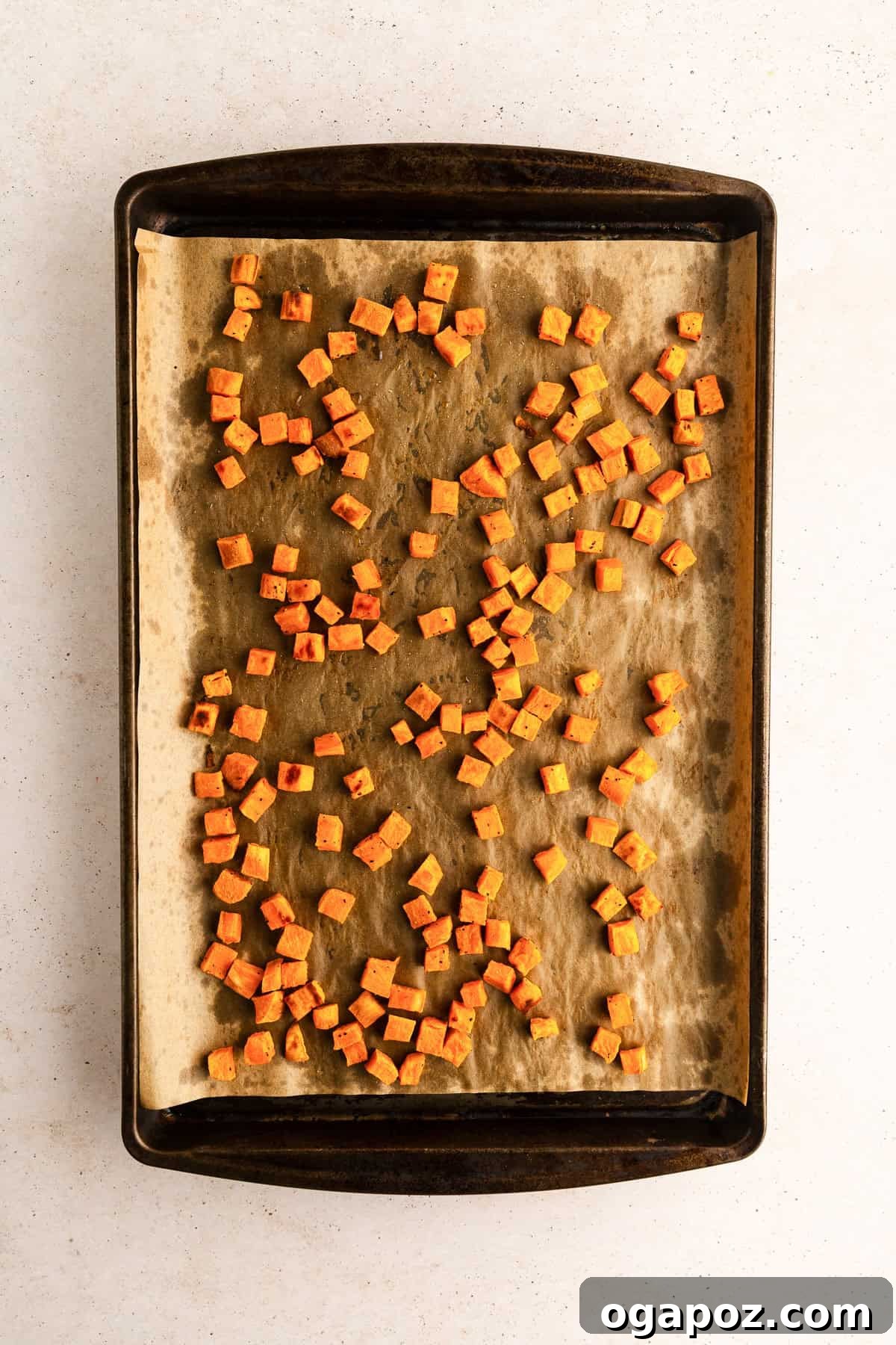 Sweet Potato cubes tossed with olive oil, salt, and pepper on a baking sheet before roasting.