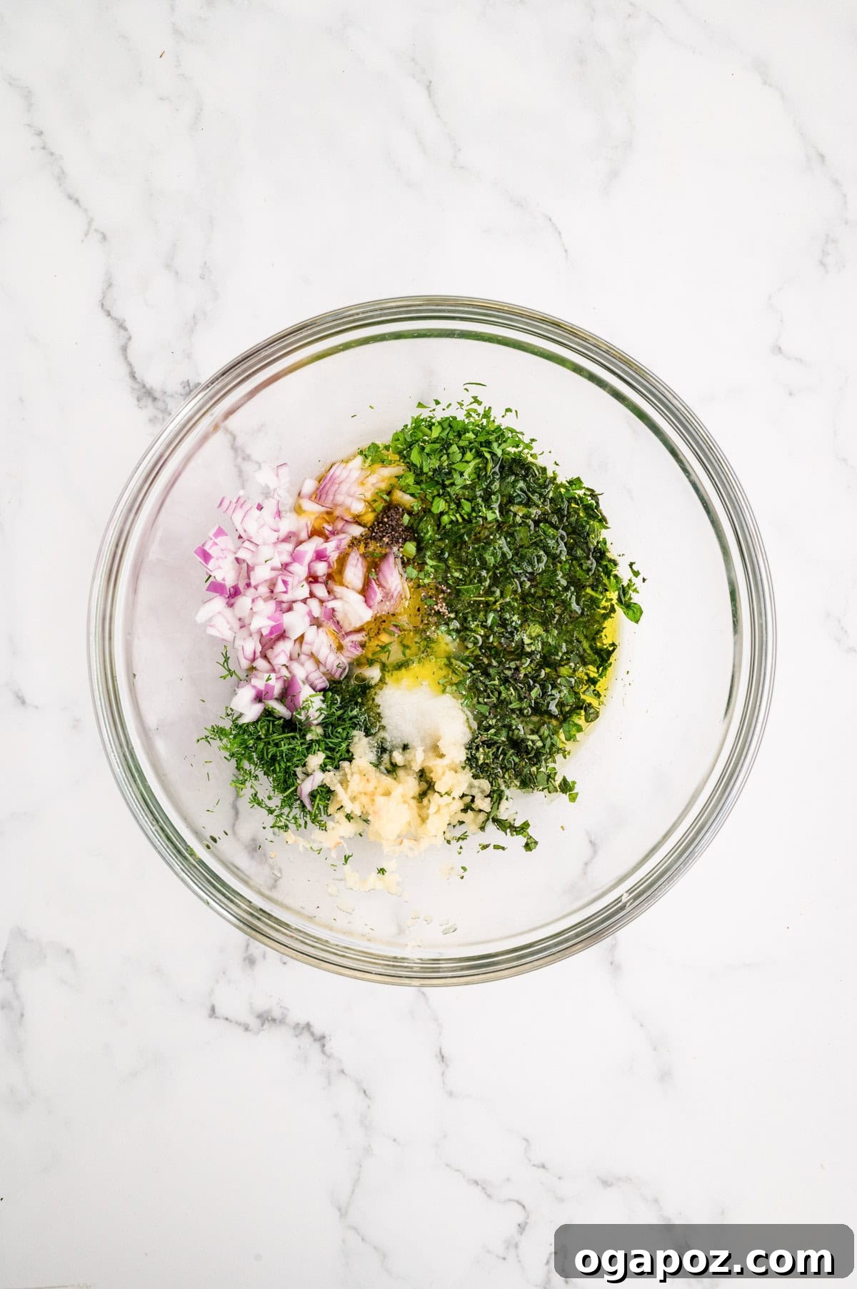 Mediterranean Chicken Breast Marinade being whisked in a bowl with fresh herbs, lemon, and olive oil.