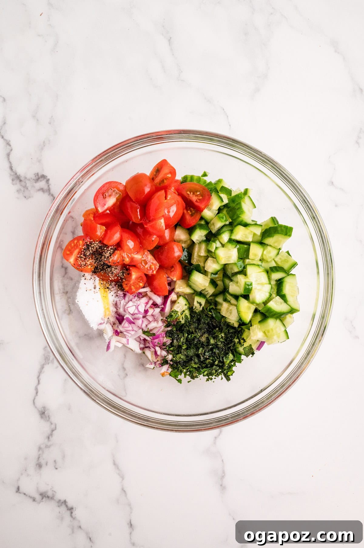 Mediterranean chicken topping ingredients: cucumber, cherry tomatoes, olives, and fresh basil, mixed in a bowl, ready to serve.
