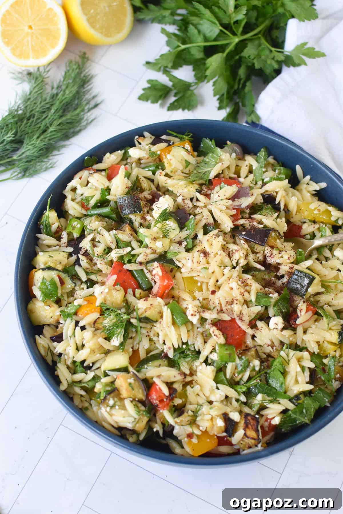 Mediterranean Roasted Vegetable Orzo Salad with Feta 2 Roasted vegetable orzo salad with feta in a blue bowl, garnished with fresh herbs