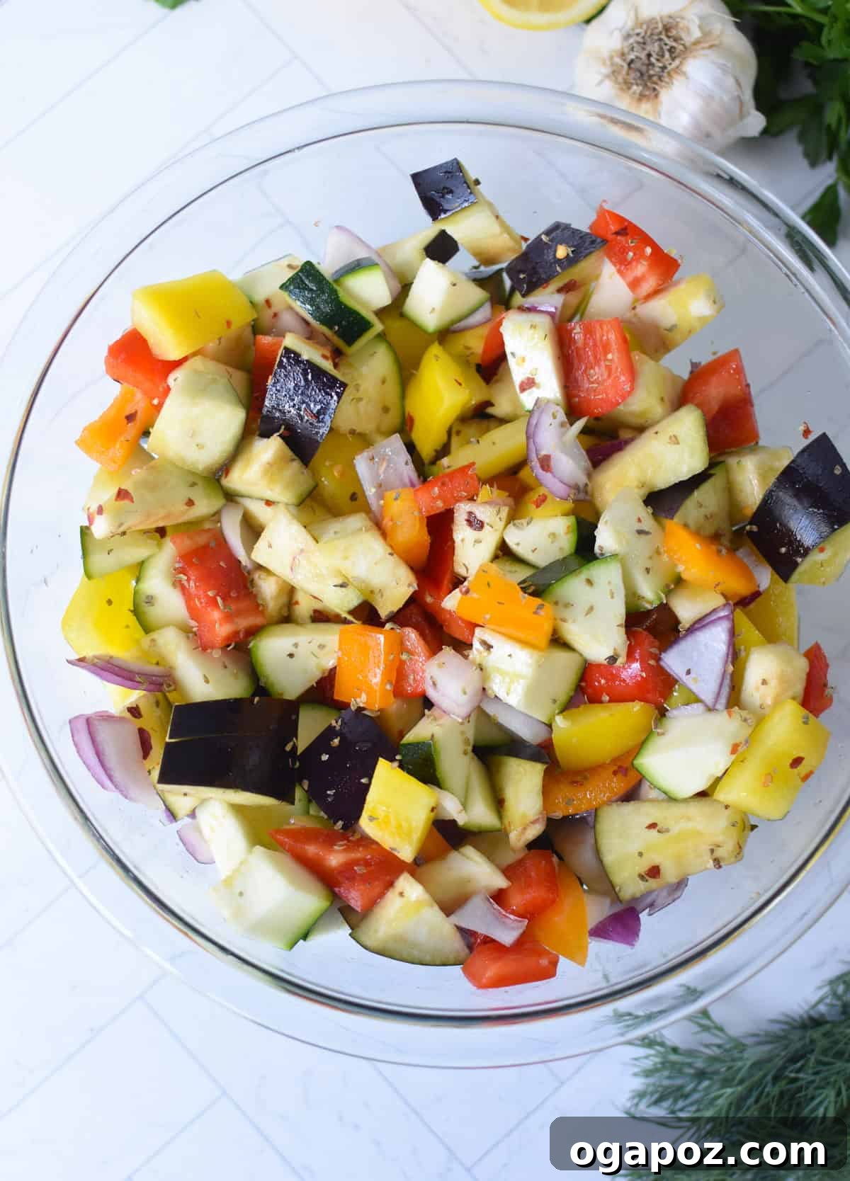 Mediterranean Roasted Vegetable Orzo Salad with Feta 7 Close-up of colorful chopped vegetables and garlic on a baking sheet, seasoned and ready for roasting