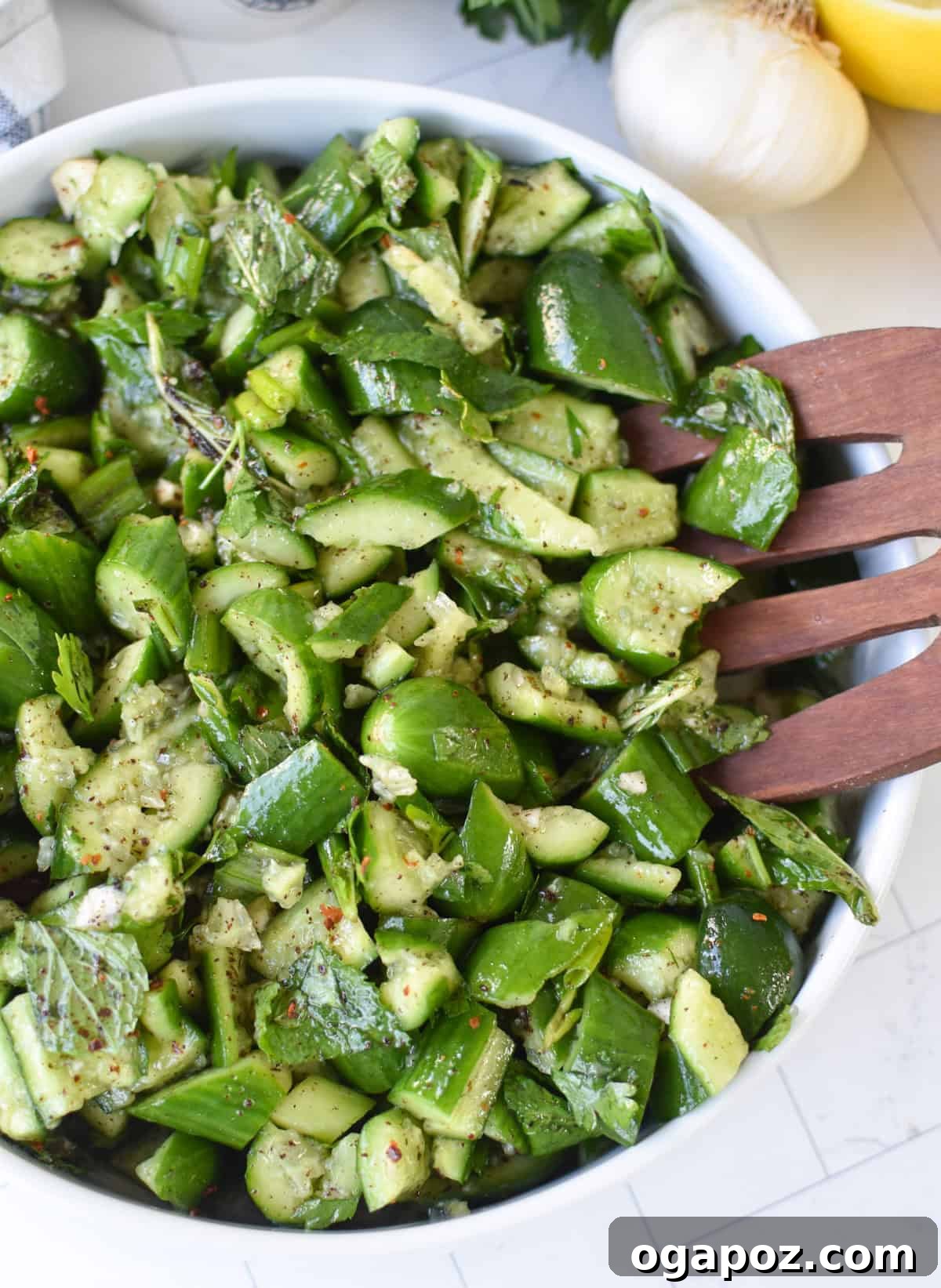 A vibrant bowl of Lebanese Smashed Cucumber Salad, garnished with fresh mint, sumac, and a drizzle of olive oil, showcasing its crisp texture.
