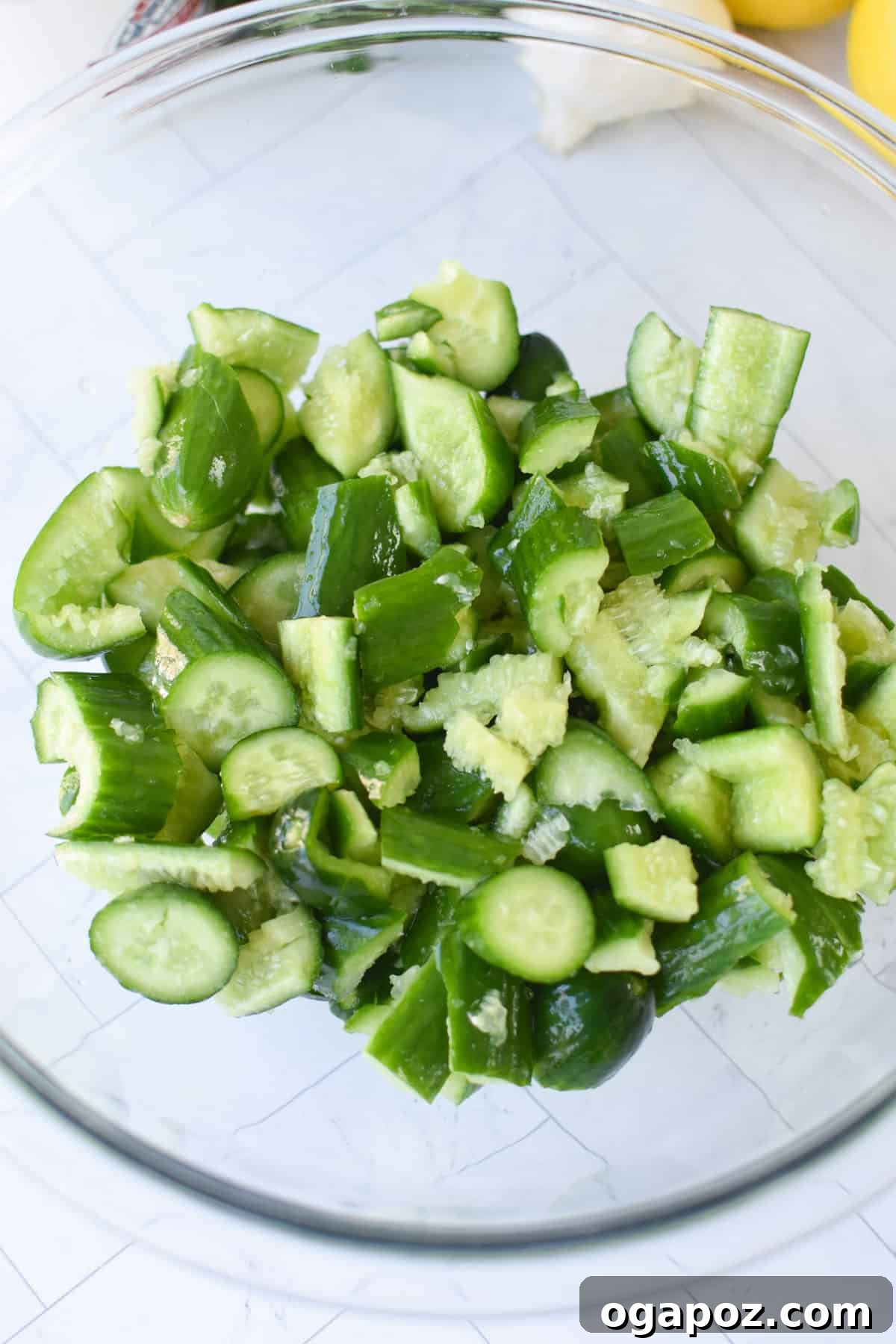 Smashed cucumber pieces in a colander, sprinkled with salt, draining excess water.