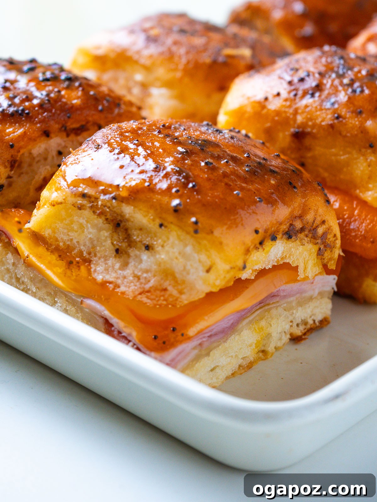 Buttery Honey-Glazed Ham & Cheese Sliders Recipe 2 Close-up of a single Hawaiian ham and cheese slider with melted Swiss cheese pulling down the side.
