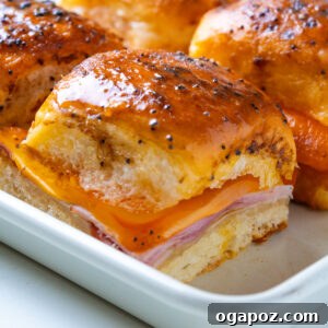 Buttery Honey-Glazed Ham & Cheese Sliders Recipe 9 Close-up of a single ham and cheese slider with melted cheese pulling down the side.