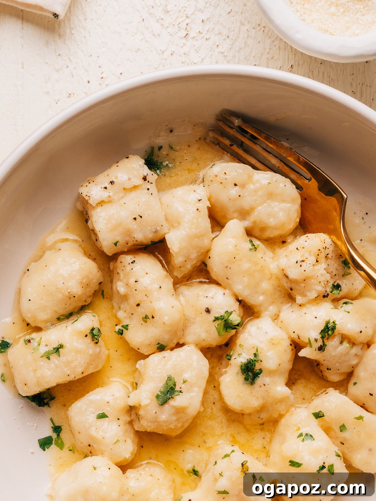 Homemade Potato Gnocchi Recipe from Scratch: Soft & Fluffy 11 Close up of potato gnocchi tossed in butter sauce with fresh parsley and black pepper.