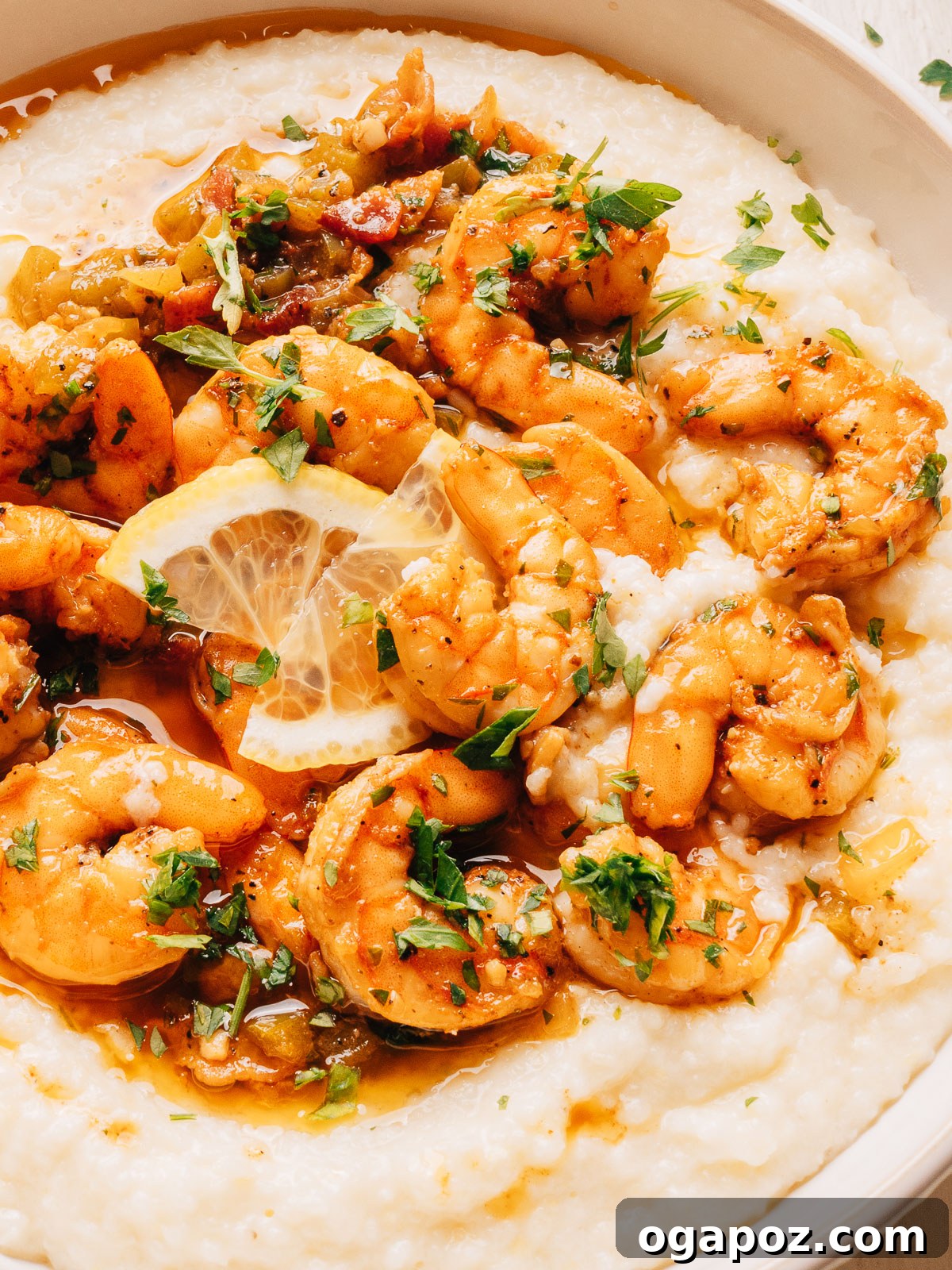 Creamy Southern Shrimp and Grits Recipe for Weeknight Dinner 11 Close-up of shrimp in a smoky bacon sauce over white cheddar grits with fresh parsley.