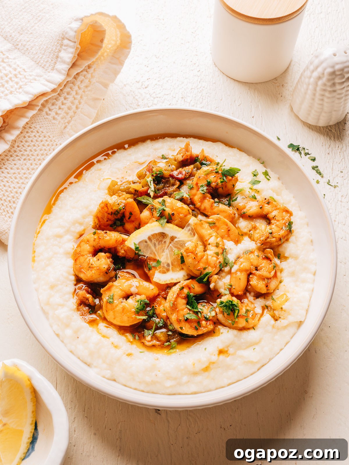 Creamy Southern Shrimp and Grits Recipe for Weeknight Dinner 9 Overhead view of a white bowl of Southern shrimp and grits with parsley and a linen napkin.