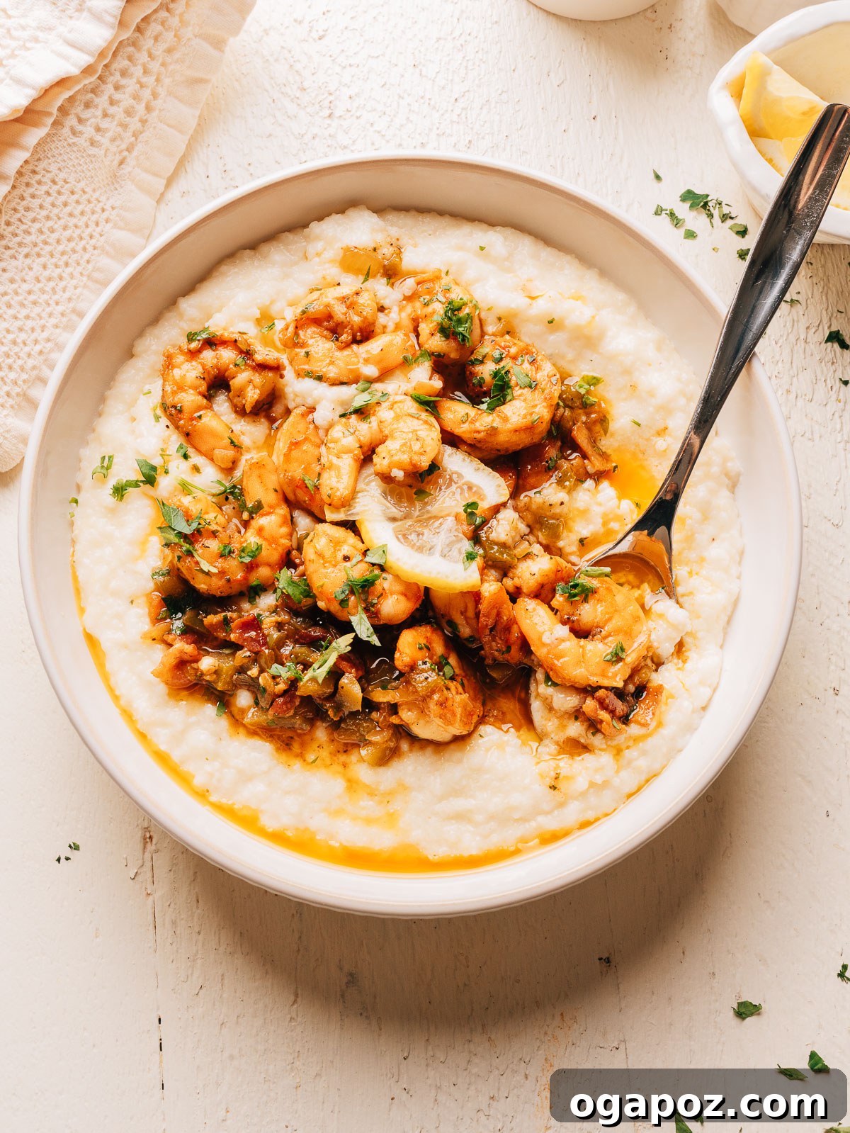 Creamy Southern Shrimp and Grits Recipe for Weeknight Dinner 10 A bowl of creamy shrimp and grits with a spoon and a small dish of lemon wedges.