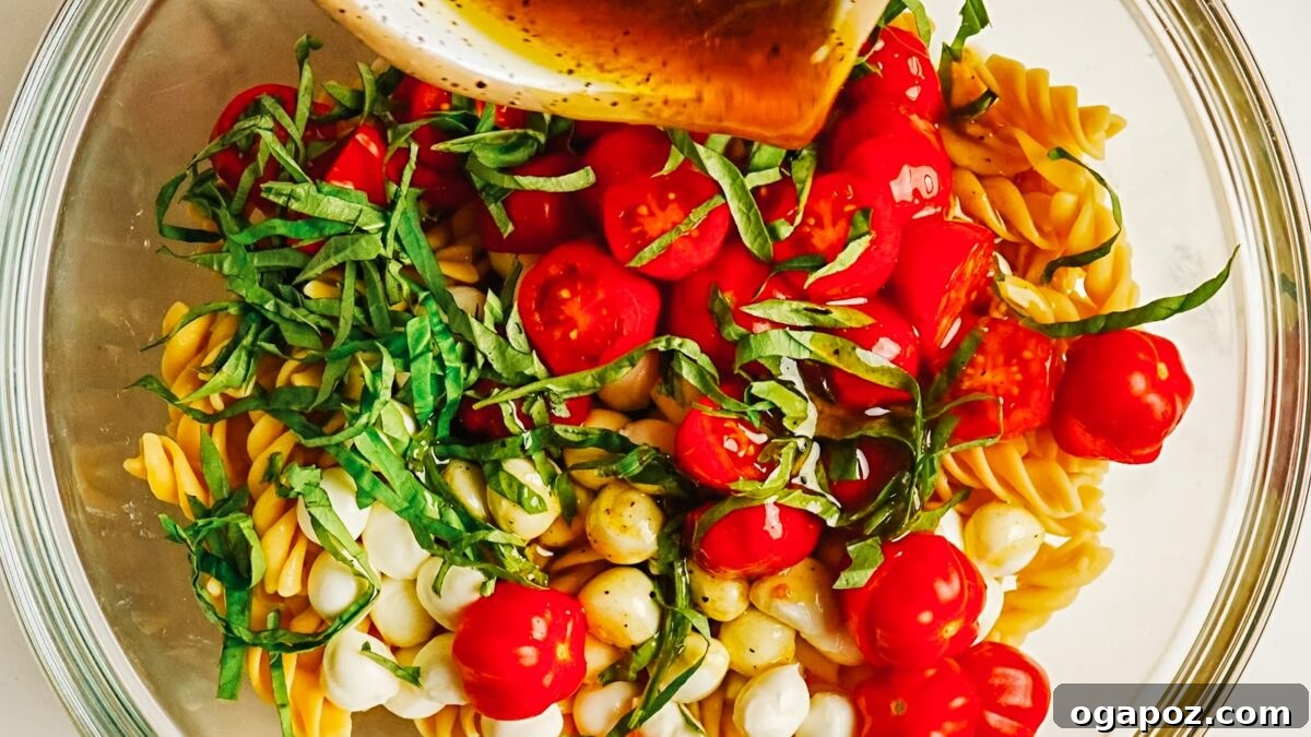 Caprese Pasta Salad with Cherry Tomatoes, Mozzarella & Basil 7 Balsamic dressing poured over caprese pasta salad before tossing.