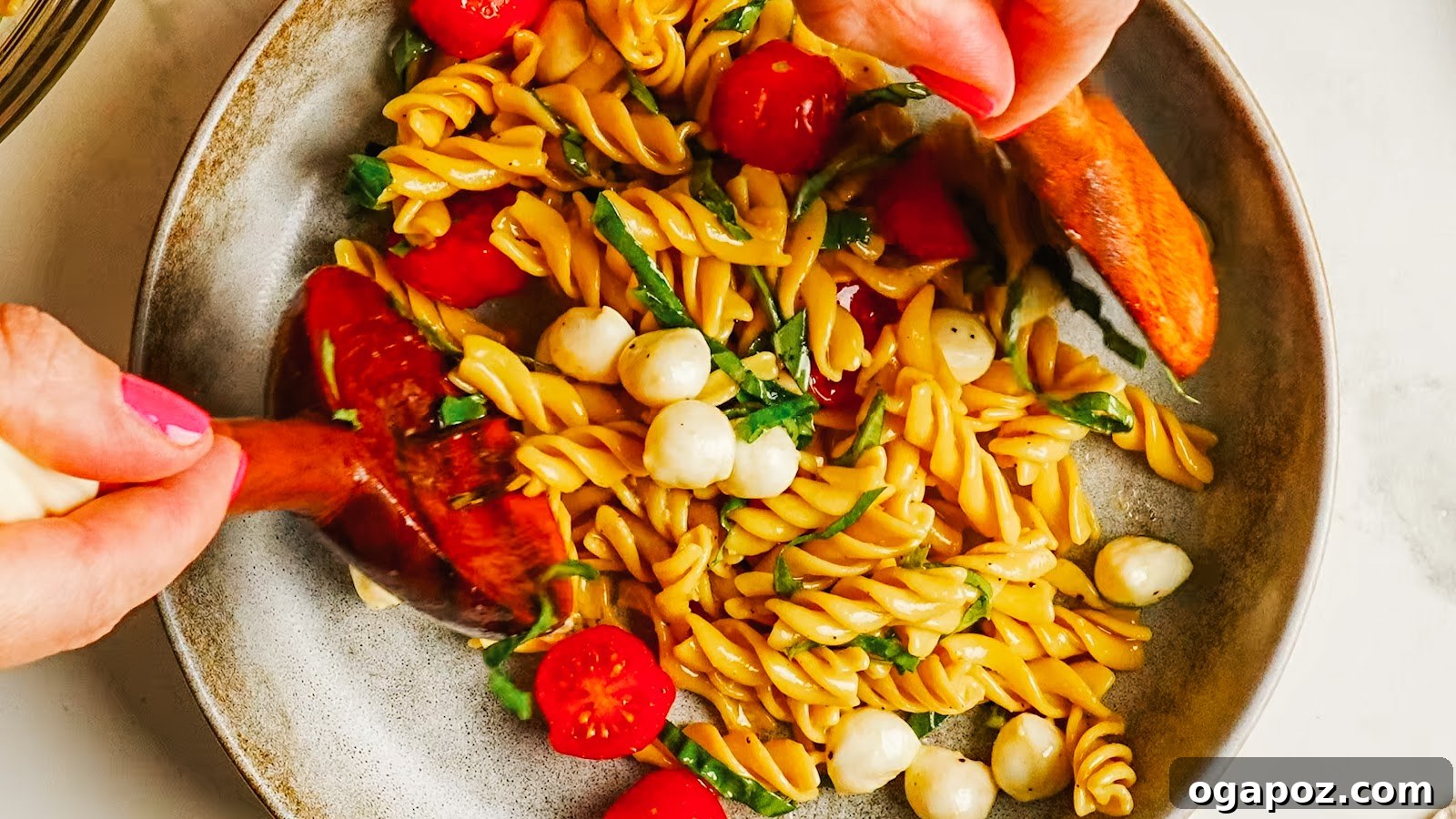 Caprese Pasta Salad with Cherry Tomatoes, Mozzarella & Basil 8 A served portion of caprese pasta salad with wooden servers.