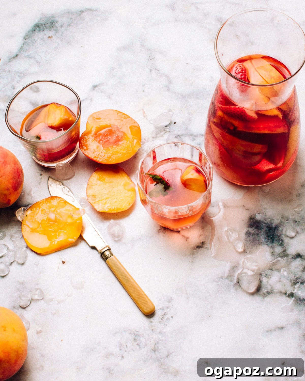 16 Summer Drink Recipes: Alcoholic and Non-Alcoholic Refreshers 3 Rosé sangria with sliced peaches and berries in a tall pitcher and glasses.