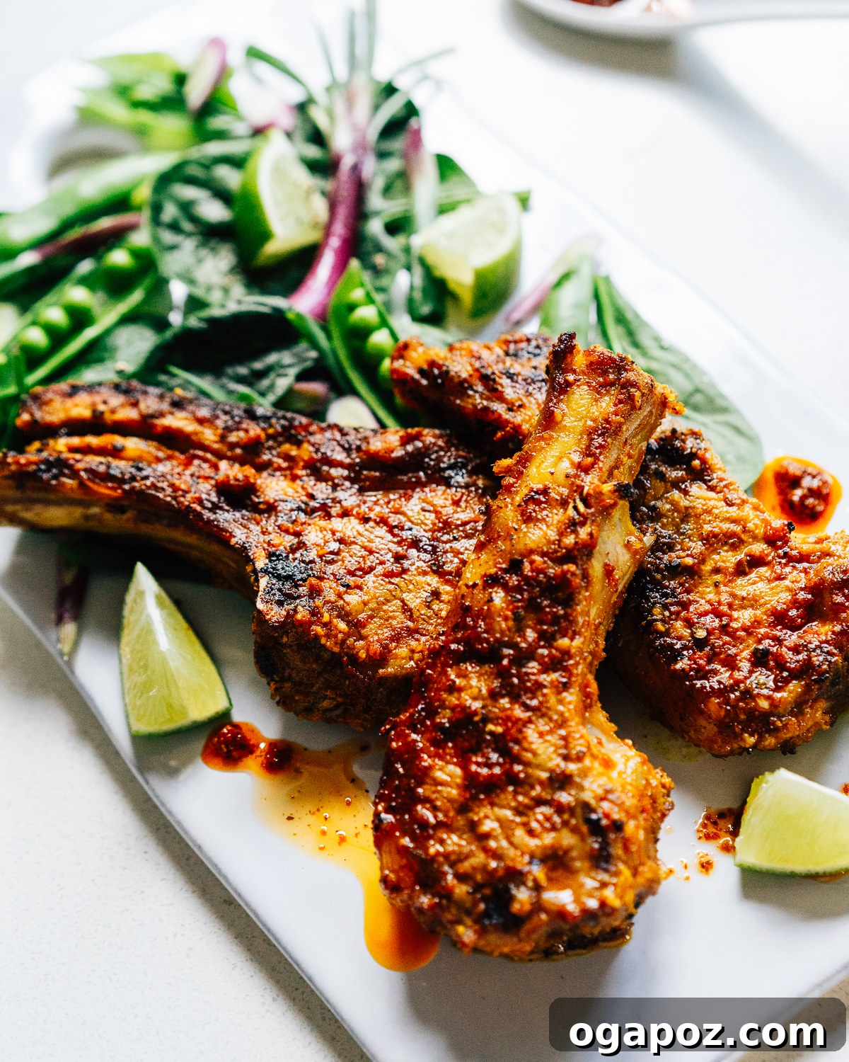 22 Summer Grilling Recipes for Crowd-Pleasing Cookouts 13 Grilled Indian lamb chops on a plate with lime wedges and salad.