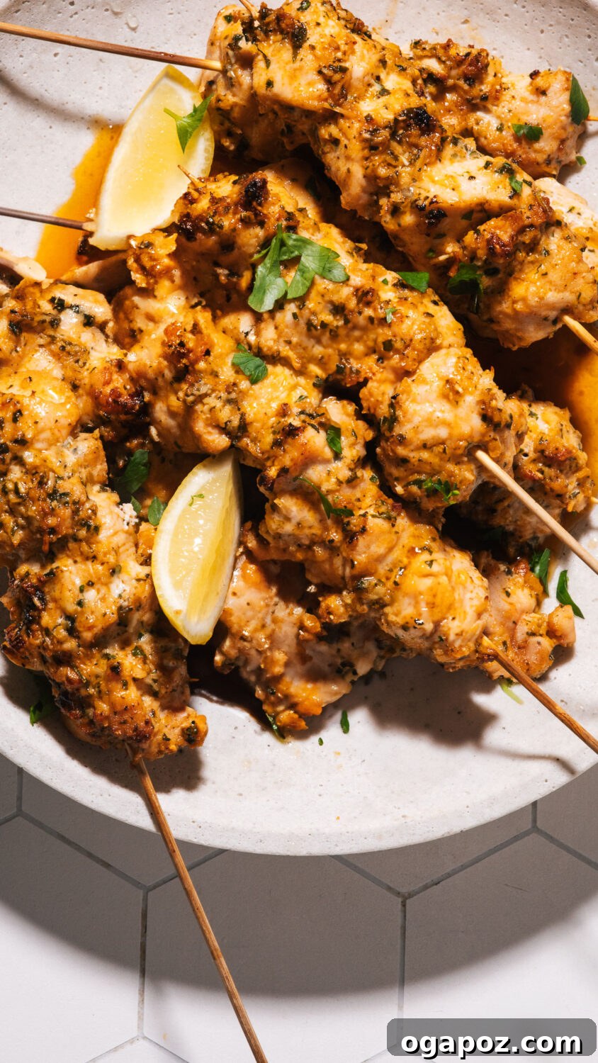 22 Summer Grilling Recipes for Crowd-Pleasing Cookouts 4 Grilled chicken skewers on a plate with lemon wedges.