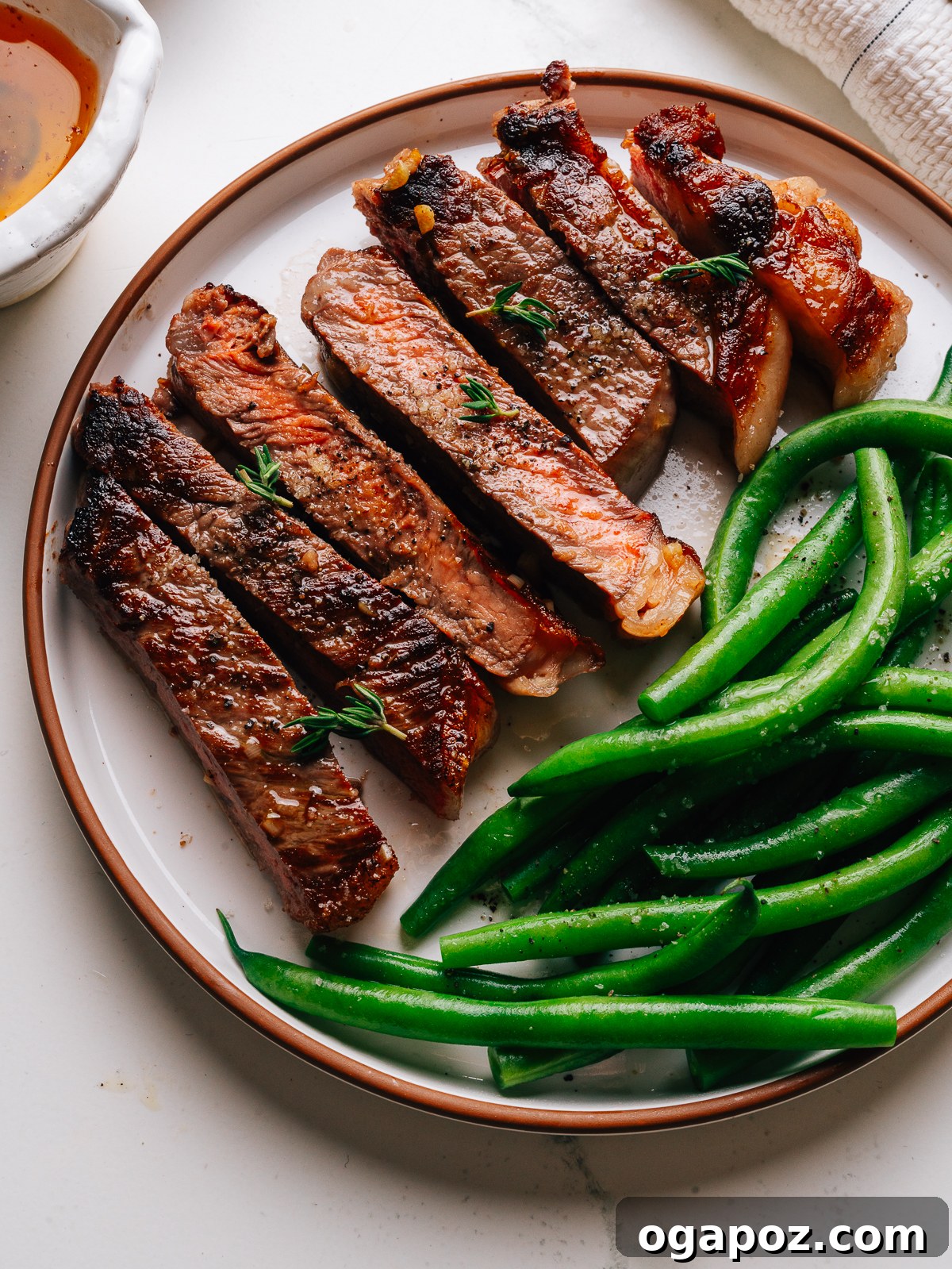 Pan-Seared Garlic Butter Steak Ready in 15 Minutes 2 Overhead of sliced garlic butter steak with green beans on a plate.