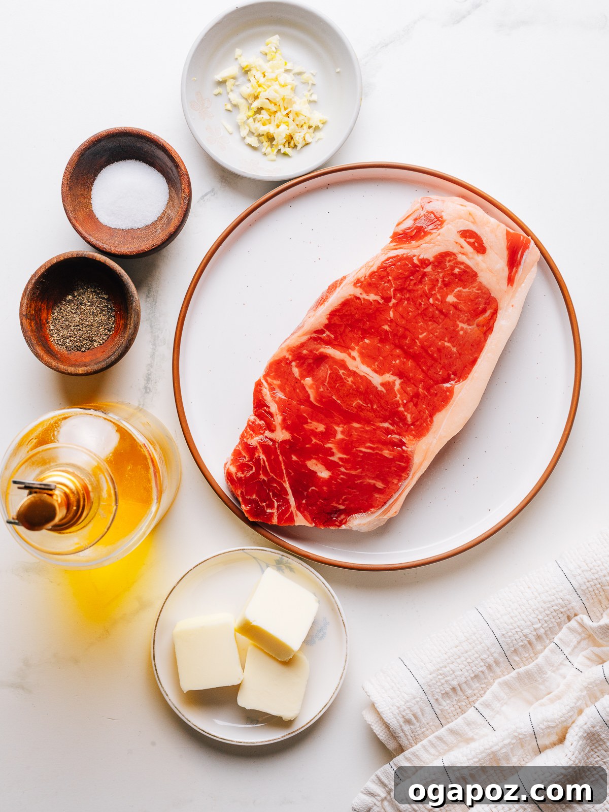 Pan-Seared Garlic Butter Steak Ready in 15 Minutes 3 Raw steak with garlic, kosher salt, and black pepper laid out for garlic butter steak.