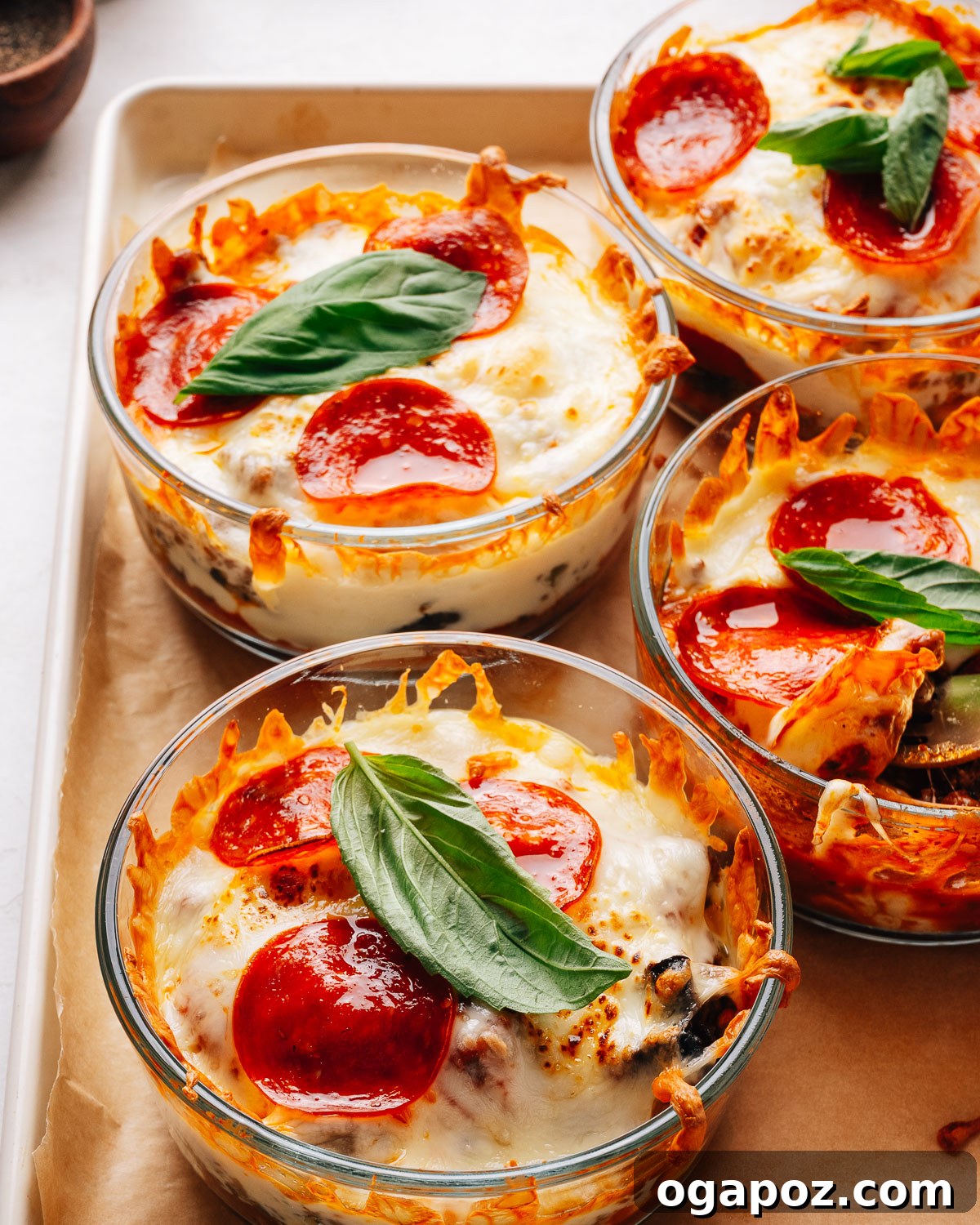 Loaded Cheesy Pizza Bowl Recipe for Weeknight Dinner 2 Pepperoni pizza bowls topped with fresh basil on a sheet pan.