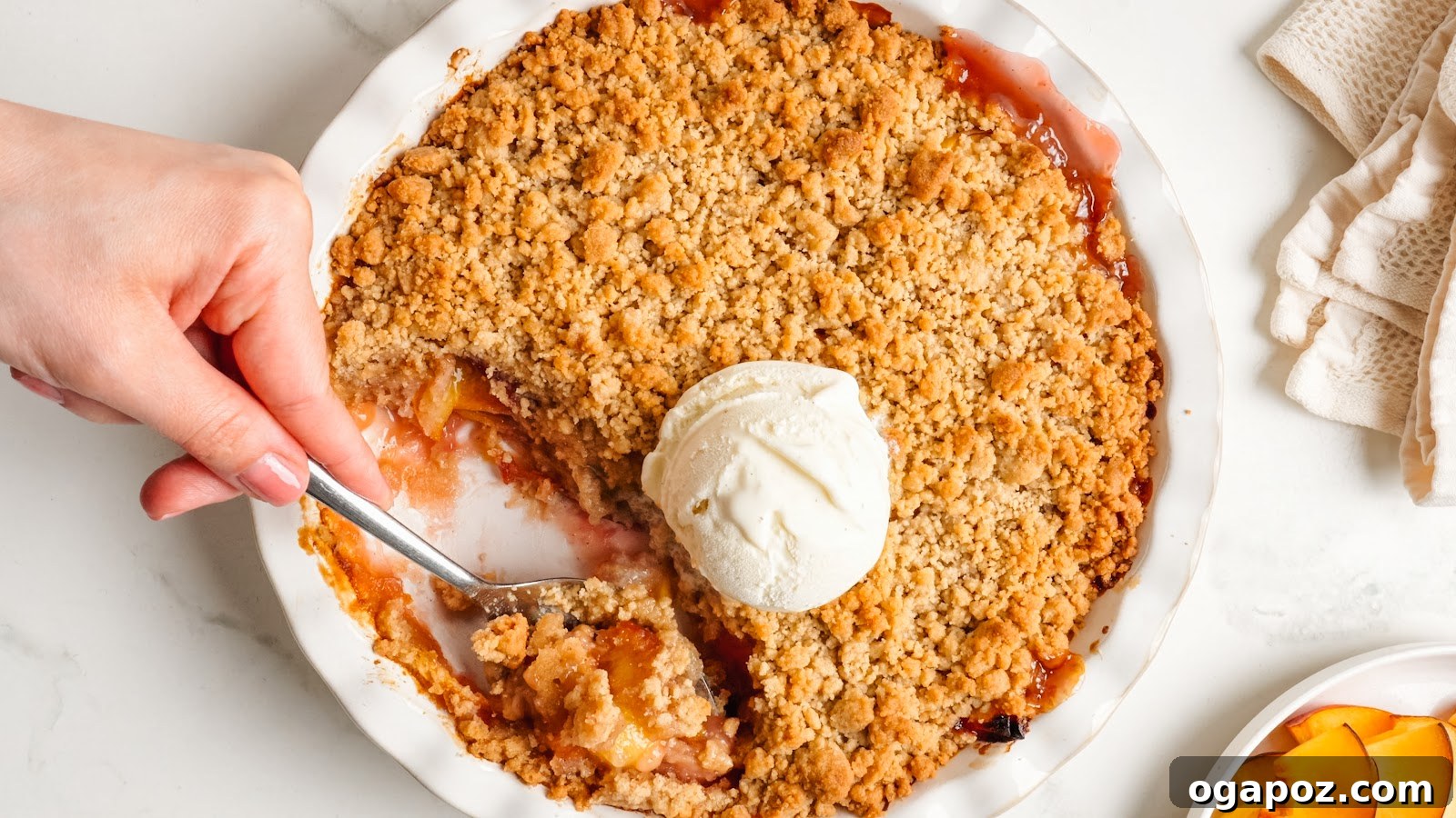 Juicy Peach Crumble with Crunchy Oat Topping 12 A spoon lifting golden brown oat crumb topping and jammy peaches from the dish.