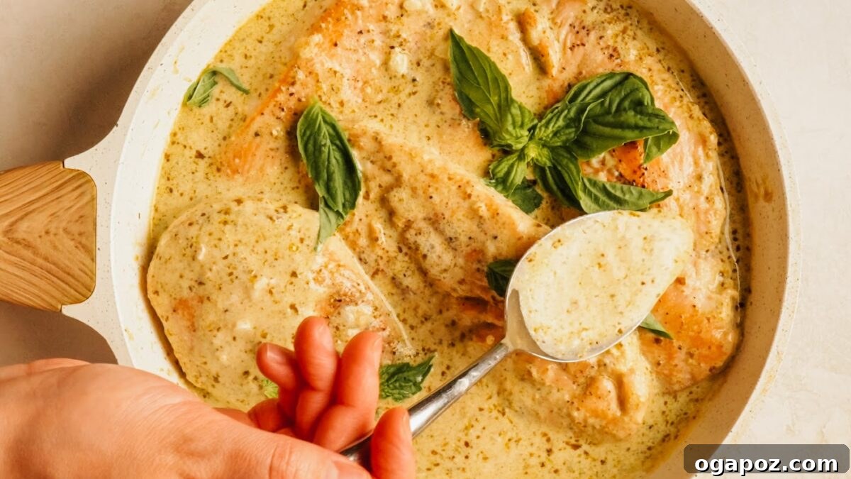 One-Pan Creamy Pesto Chicken in 30 Minutes 8 Overhead creamy pesto chicken with fresh basil and a serving spoon.