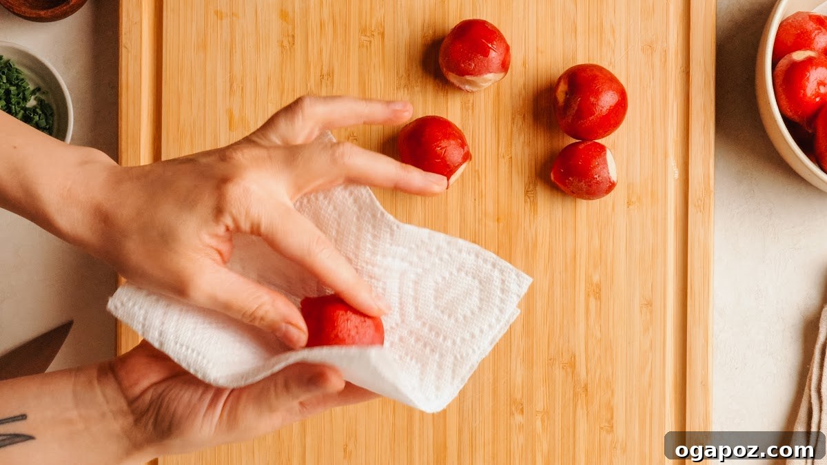 Crispy Oven-Roasted Radishes with Garlic and Herbs 5 Fresh whole radishes being patted dry on a wood cutting board.