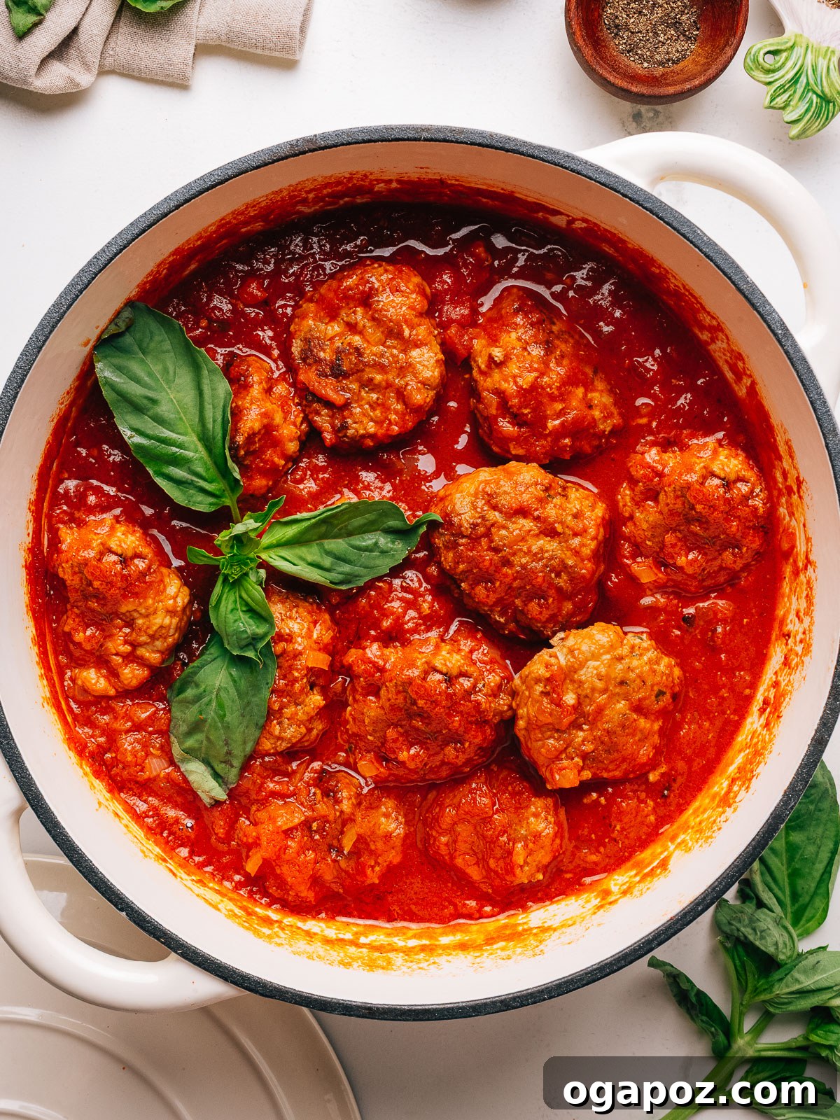 Classic Italian Meatballs in Rich Tomato Sauce 2 Italian meatball recipe in a pan with fresh basil leaves.