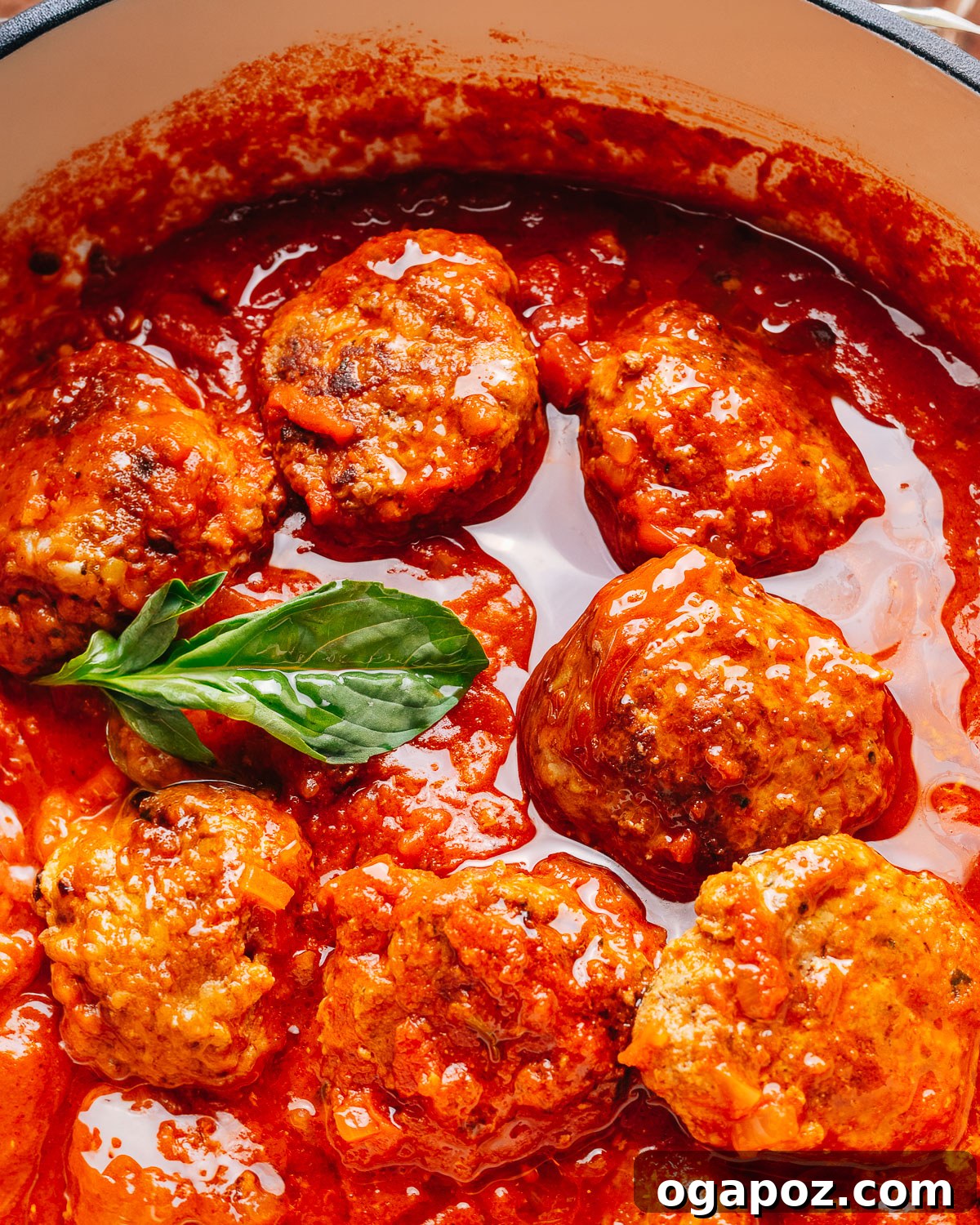 Classic Italian Meatballs in Rich Tomato Sauce 12 Italian meatball recipe in a pan with a spoon.