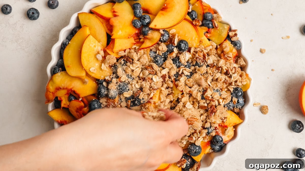 Peach Blueberry Crisp with Brown Sugar Oat Topping 8 Sprinkling the oat crumble topping over the fruit.