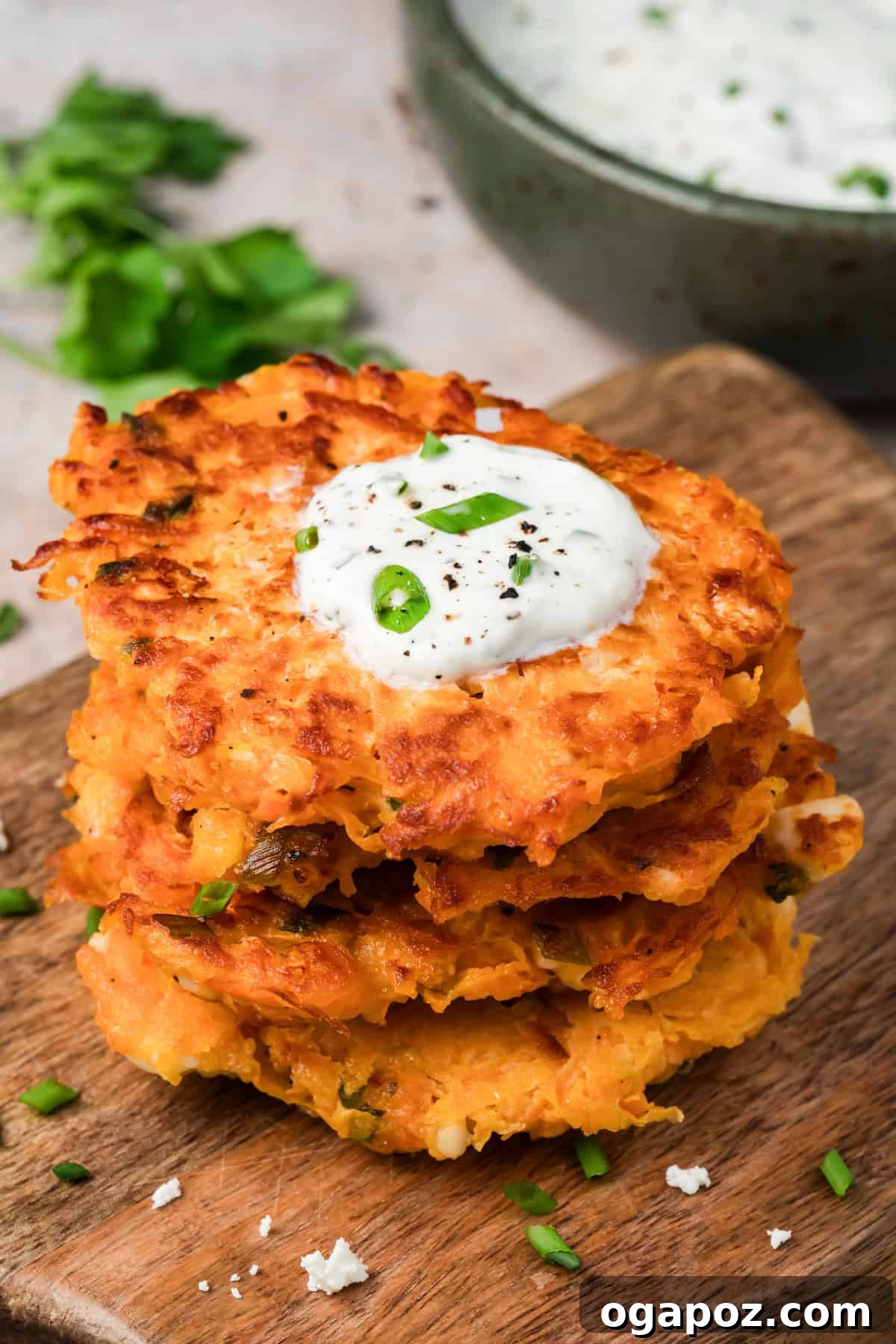 Crispy Sweet Potato Fritters with Herb Yogurt Dip 2 Crispy sweet potato fritters with feta stacked on a plate with lemon herb yogurt sauce
