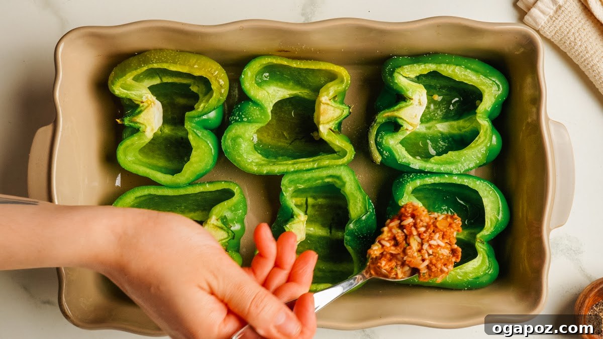 Classic Stuffed Green Peppers with Rice and Ground Beef 9 Spooning filling into charred green pepper halves.