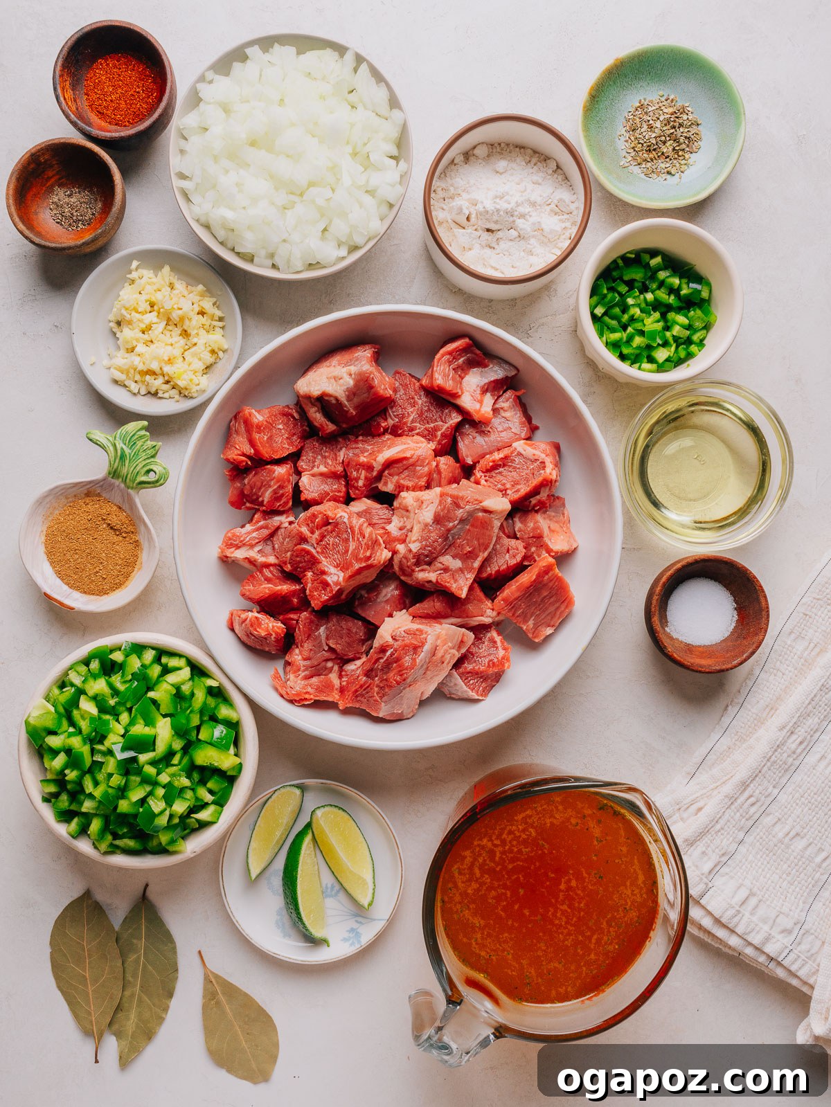 Authentic Mexican Carne Guisada: Hearty Beef Stew Recipe 3 Ingredients for carne guisada laid out in bowls, including cubed beef, peppers, onion, spices and broth.