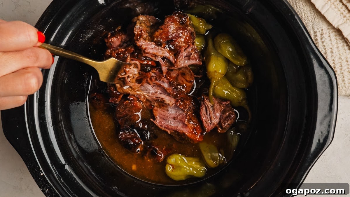 Slow-Cooker Mississippi Pot Roast Recipe for Tender, Flavorful Meat 9 Shredding the cooked beef with two forks in its buttery juices.