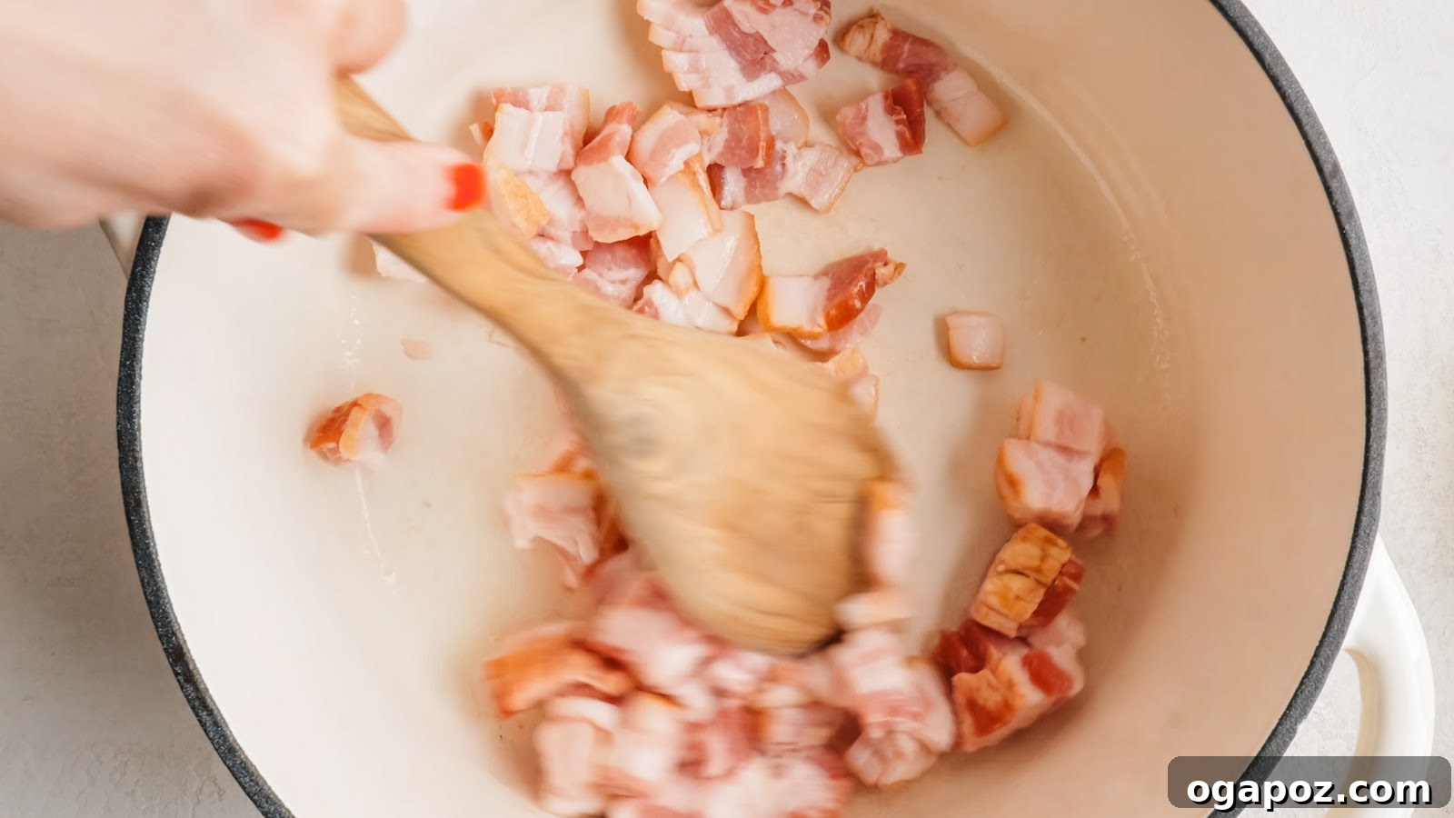 Chopped thick-cut bacon rendering in a Dutch oven.