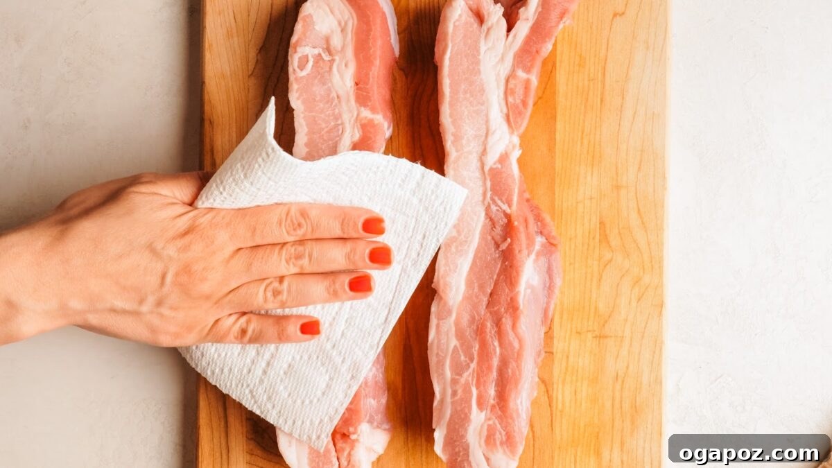 Raw skin-on pork belly slab being patted dry with a paper towel.