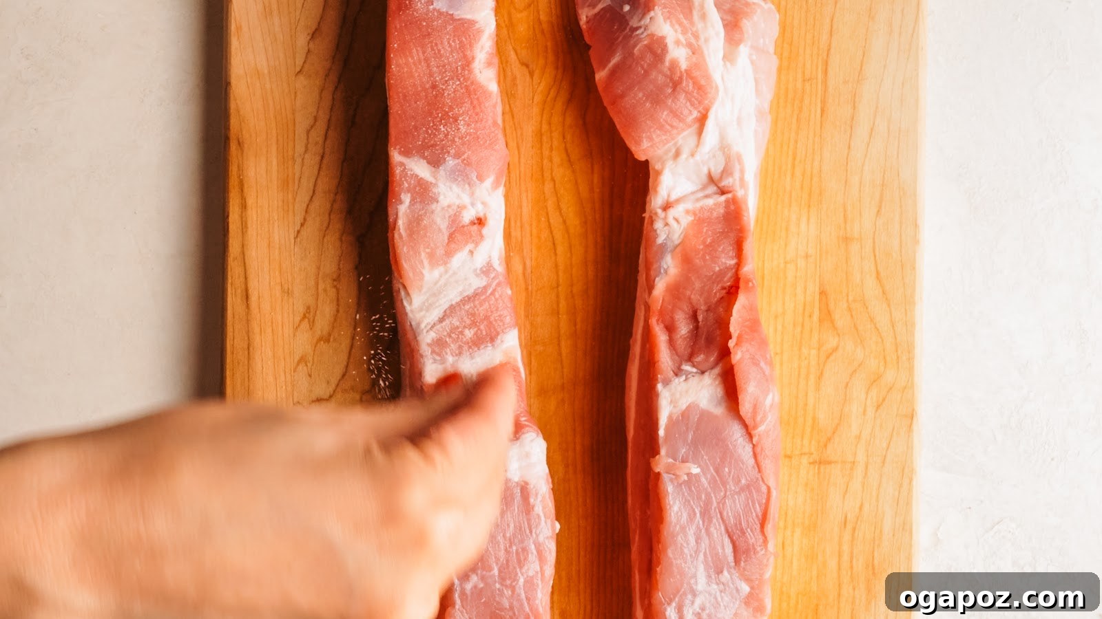 Seasoning the meat side of the pork belly on a cutting board.