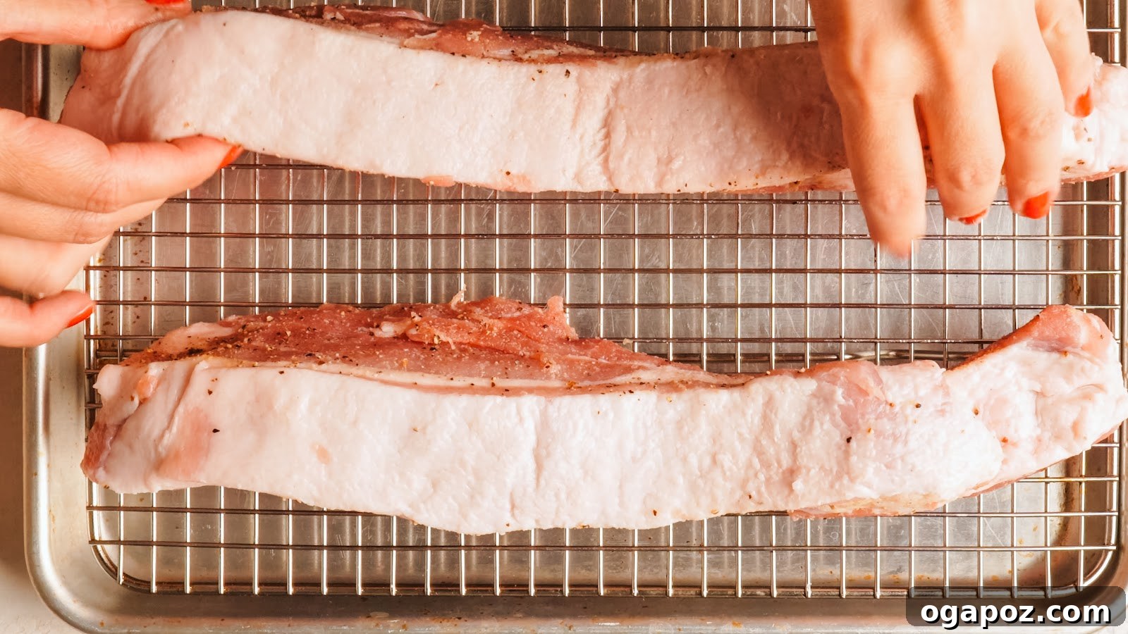 Pork belly set skin side up on a wire rack over a rimmed tray.