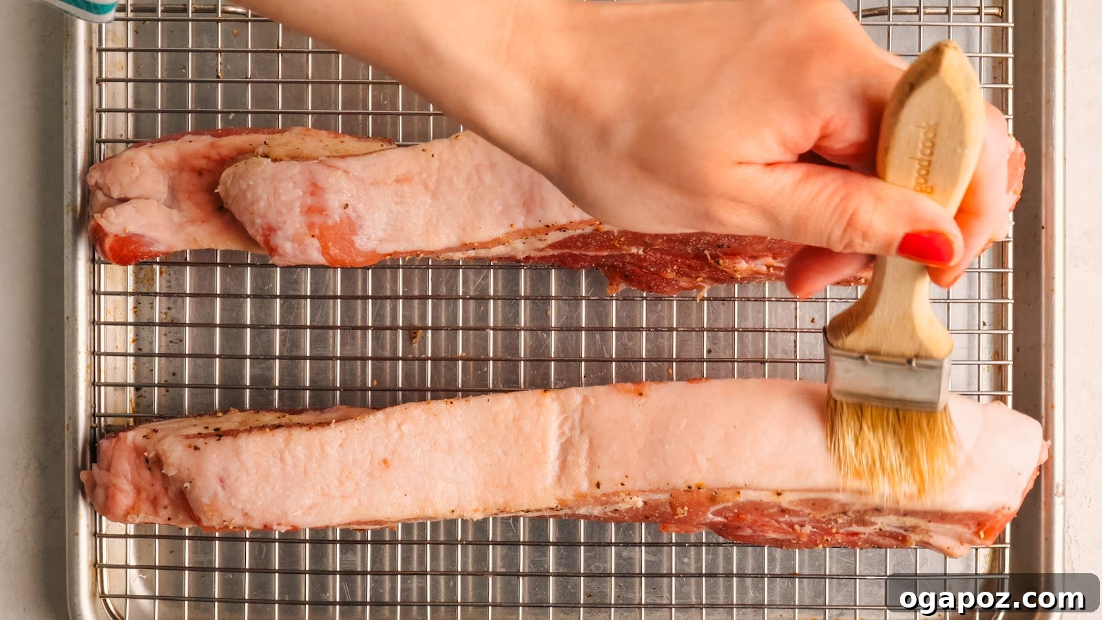 Brushing kosher salt over the pork belly skin on the rack.