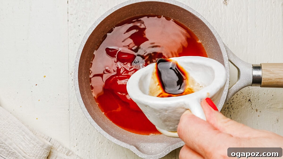 Adding the liquid ingredients to the honey BBQ sauce in a saucepan.