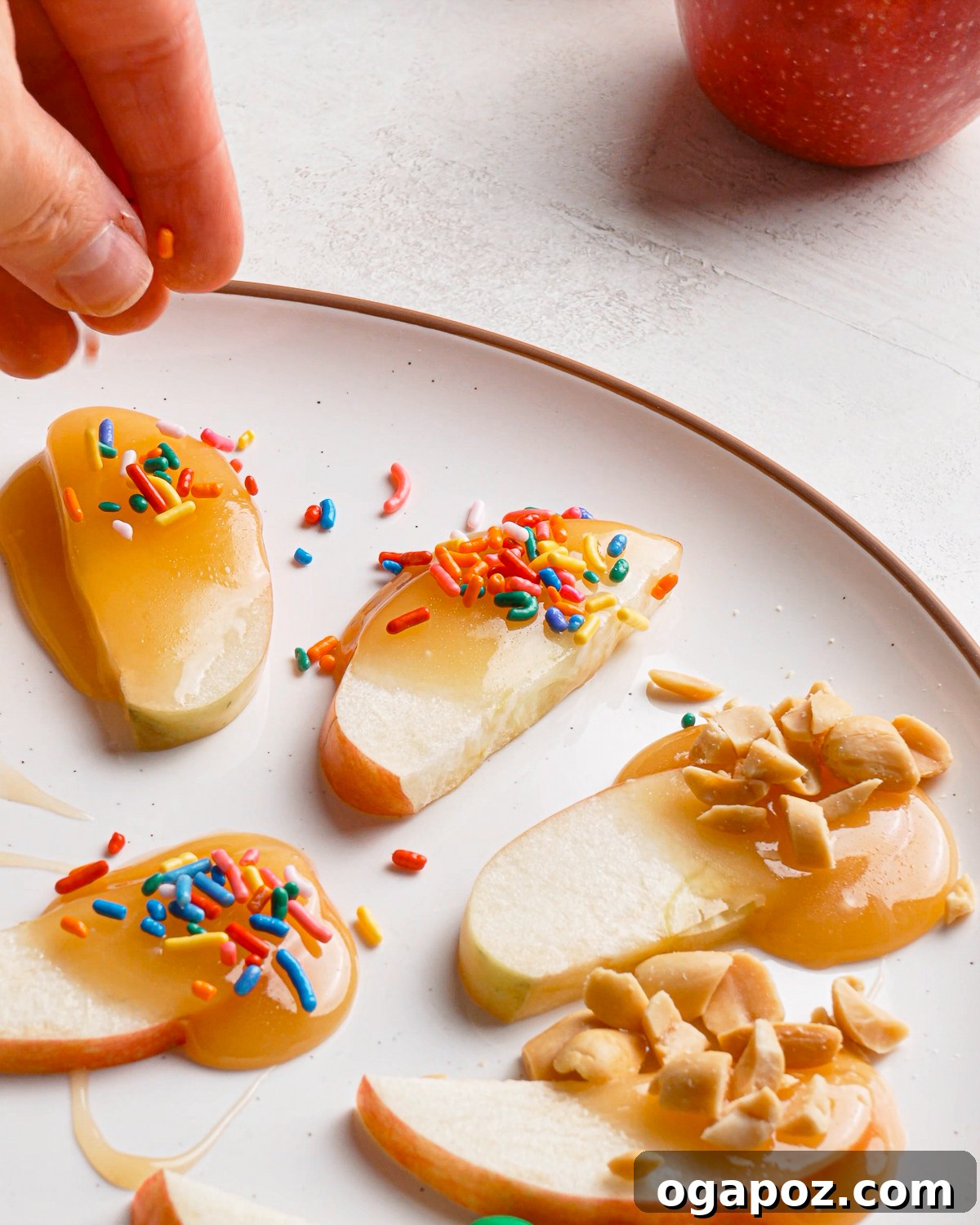 Adding sprinkles to caramel apple slices before the caramel sets.