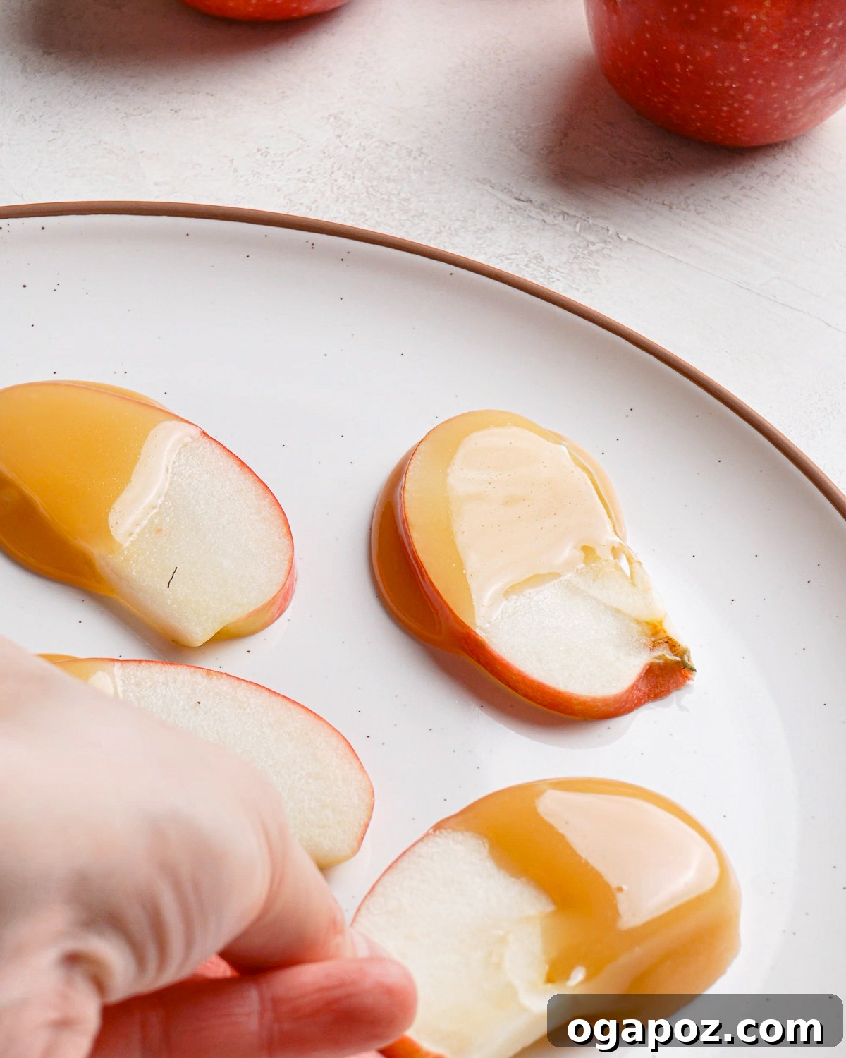 Picking up a caramel coated apple slice from a plate.