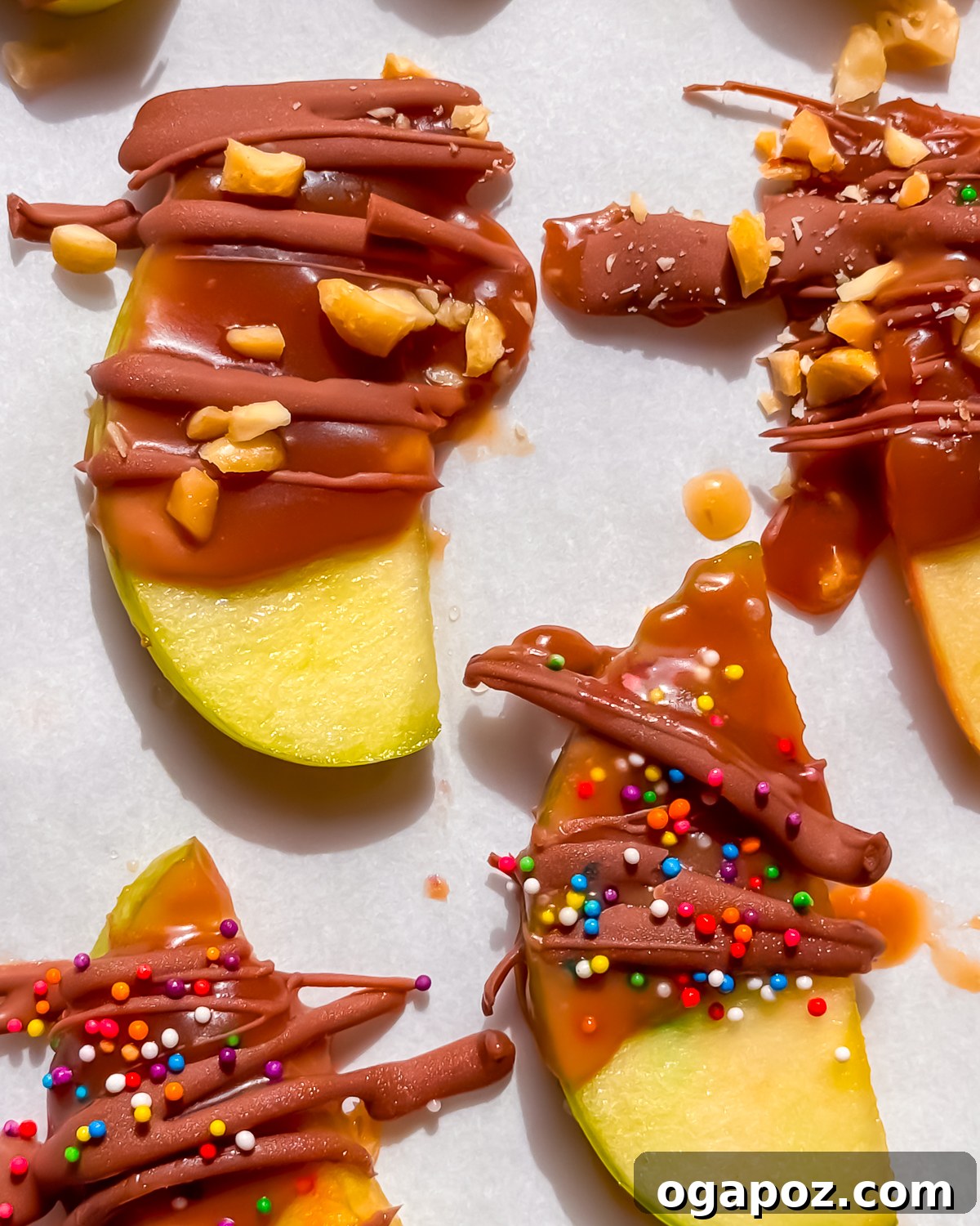 Overhead tray of caramel apple slices topped with chocolate, peanuts and candy.