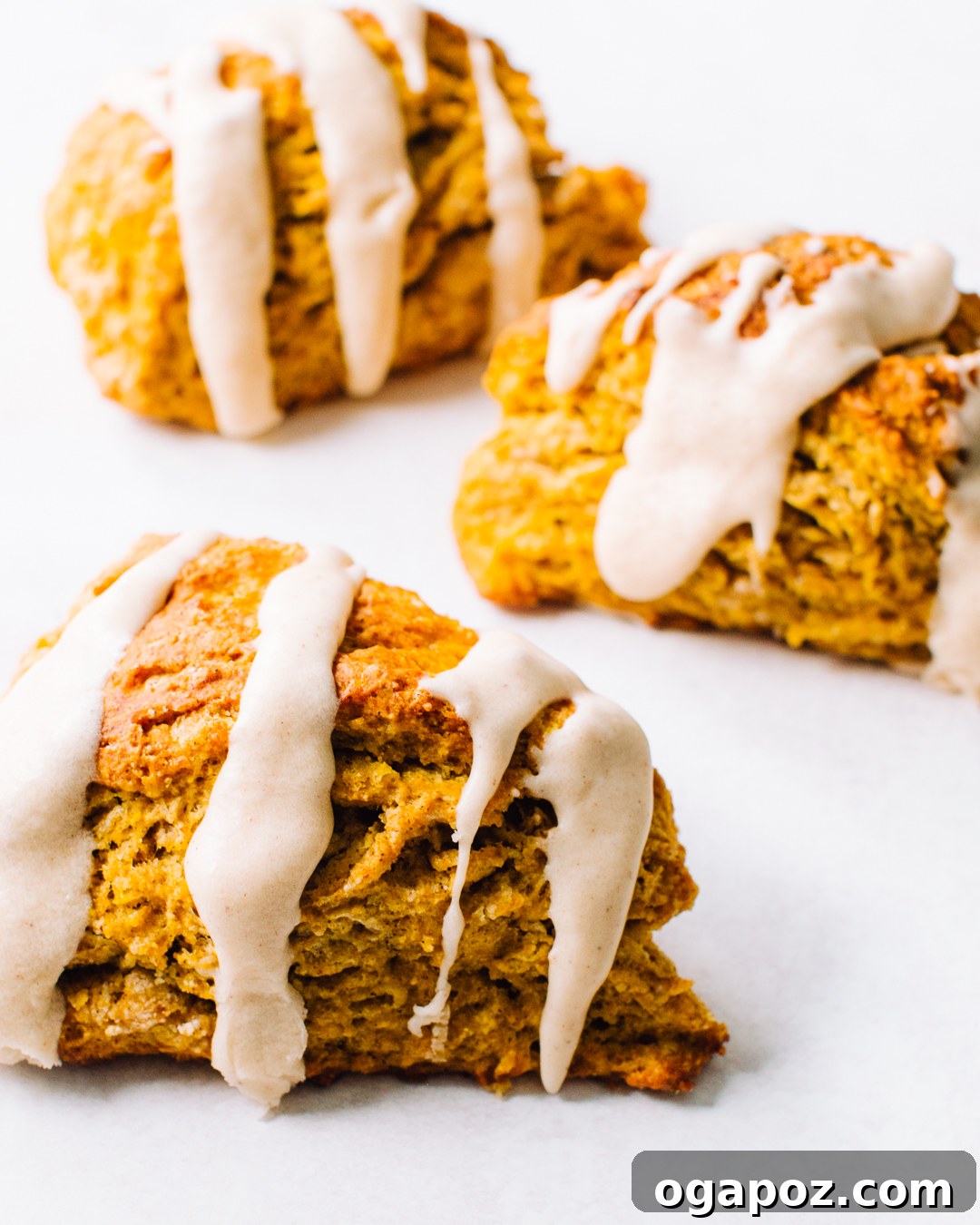 Pumpkin scones drizzled with cinnamon glaze on a white background.